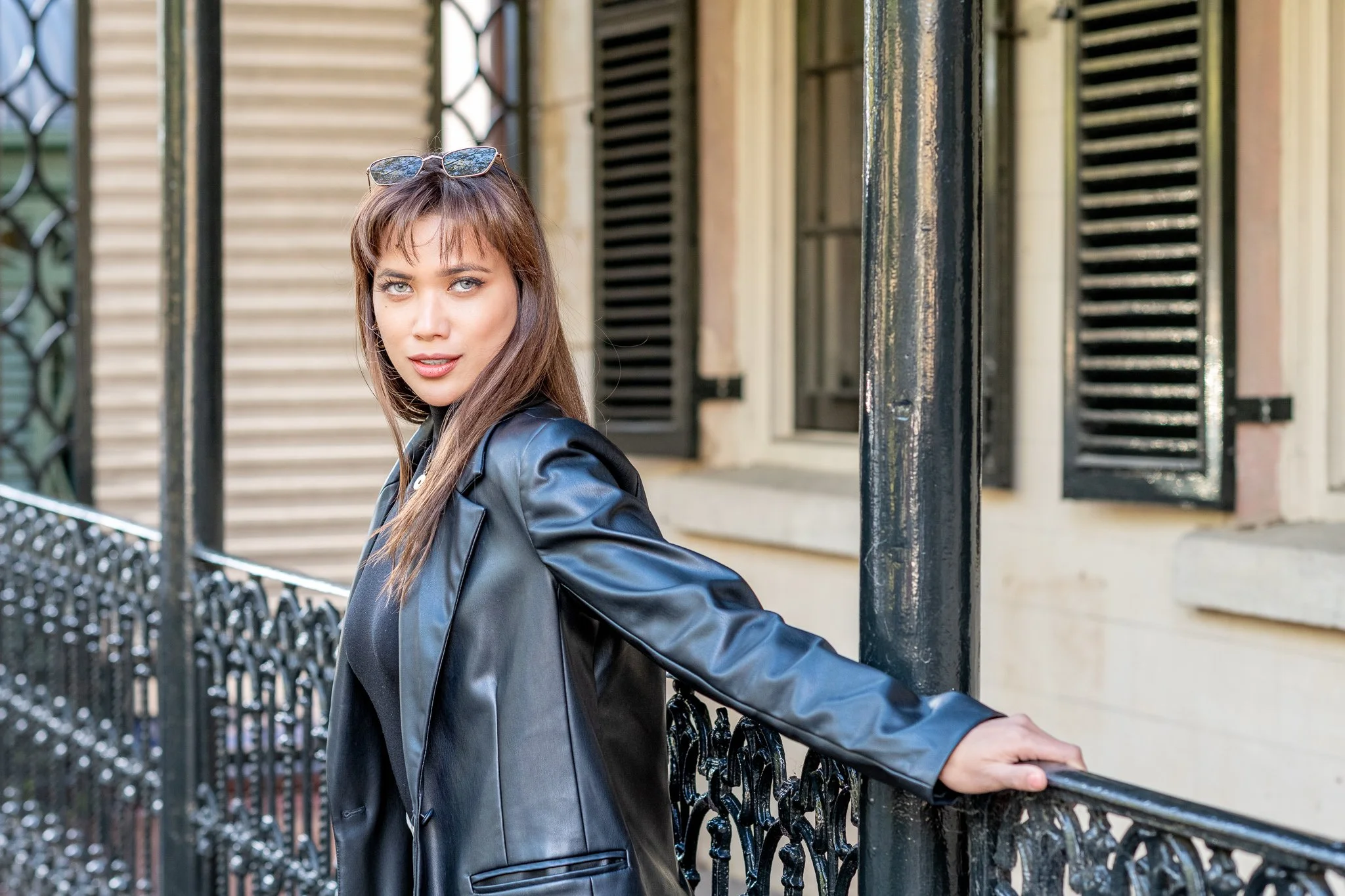 Woman posing for an urban lifestyle branding portrait beside a verandah with shutters and columns.