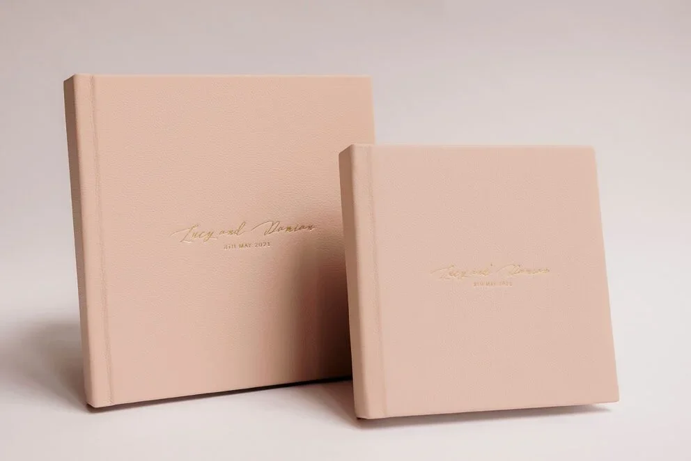 Two custom wedding photo albums with soft pink covers displayed as finished printed keepsakes.