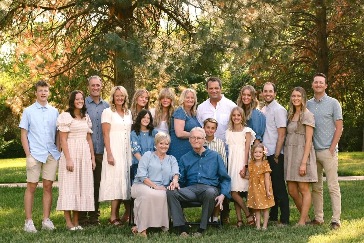 Extended family gathered together for a formal outdoor portrait in a park setting.