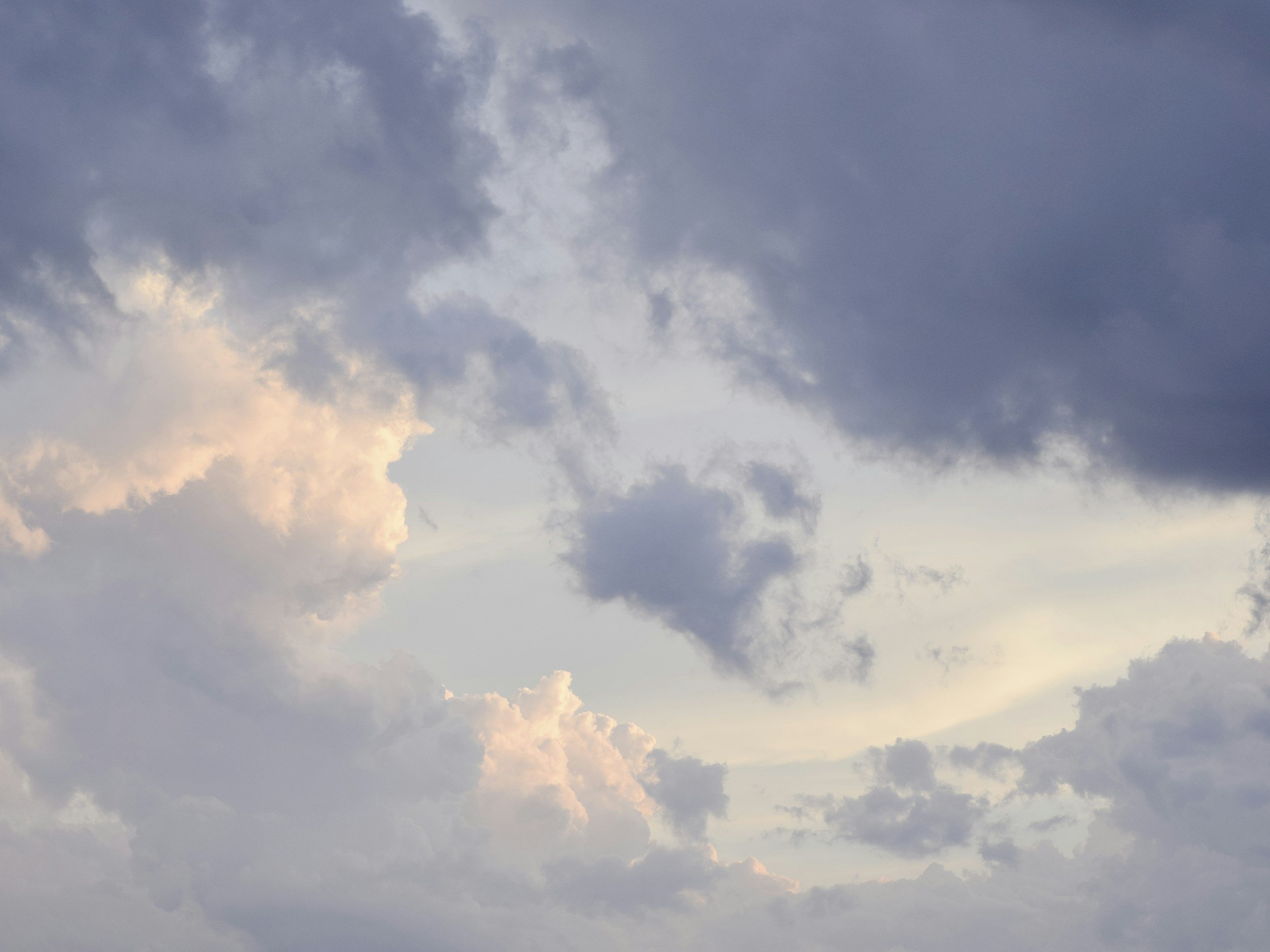 Overcast sky with clouds, partially illuminated by sunlight.