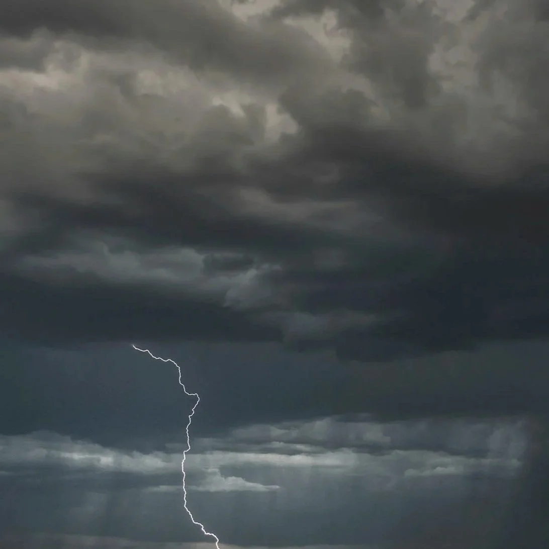 Dark stormy clouds with a lightning bolt striking down from the sky.