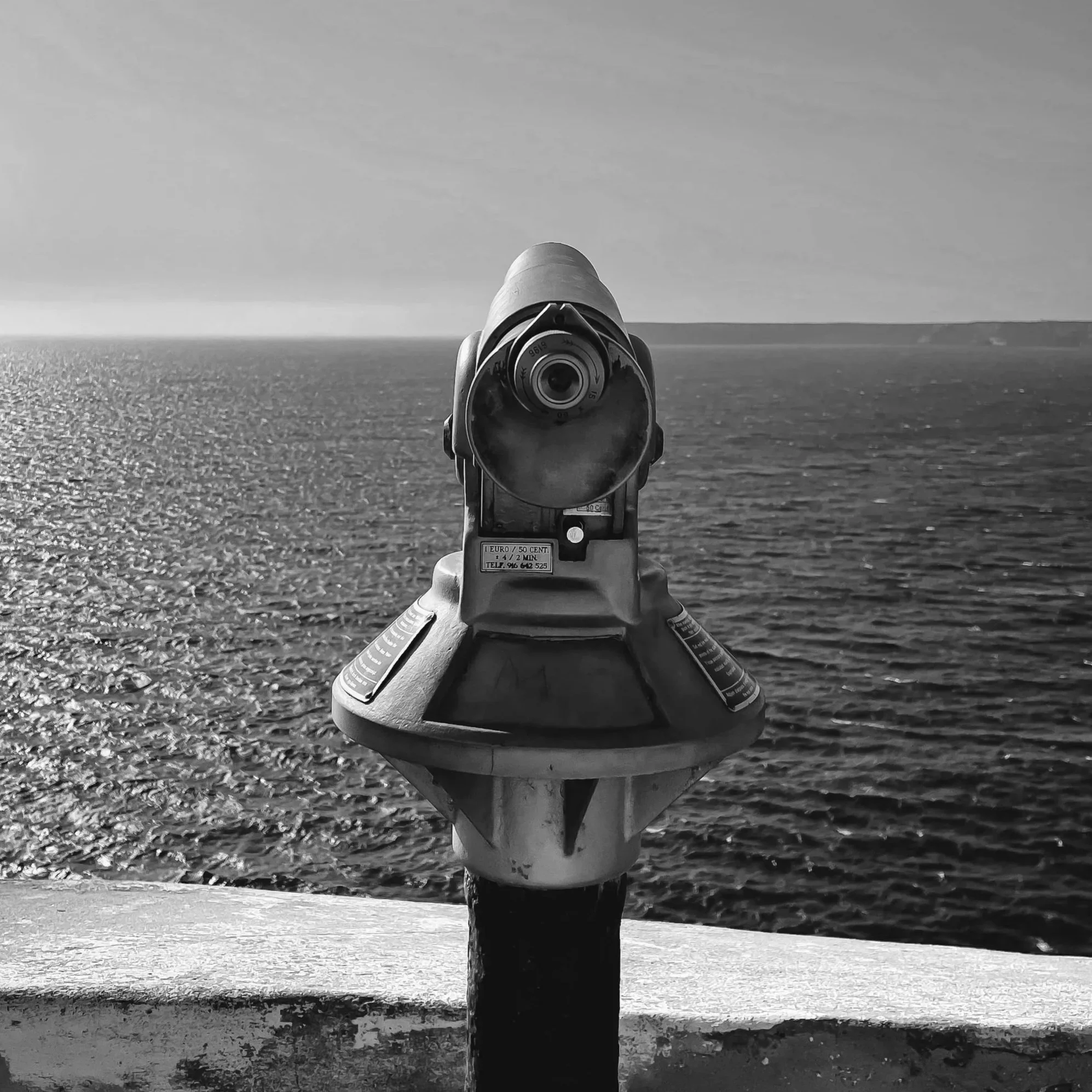 View through telescope of the ocean horizon with a cloudy sky.
