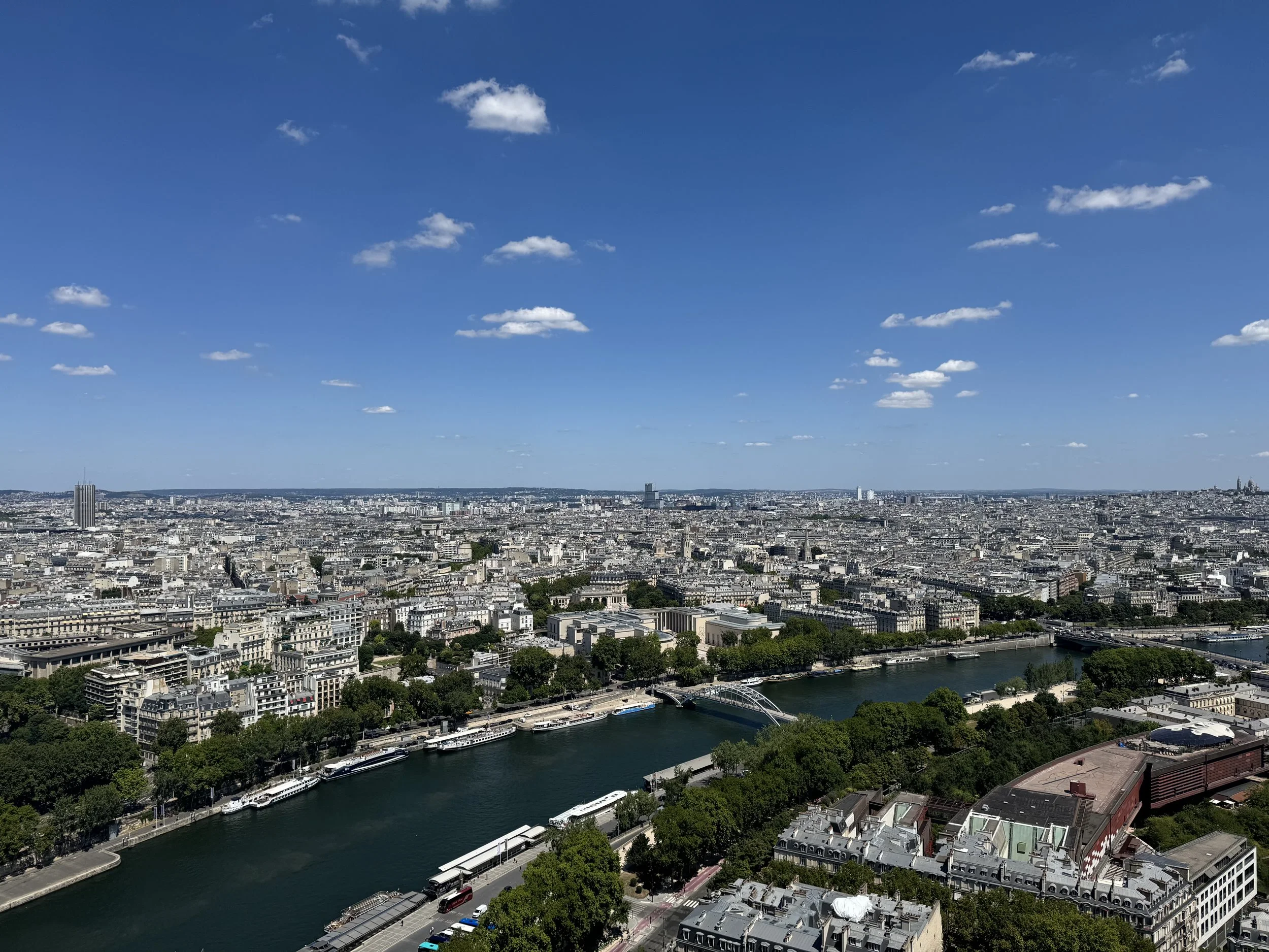 A sweeping cinematic panorama of the Parisian cityscape, capturing the Seine River, historic architecture, and modern skyline under a pristine sky, KLA. Media production.