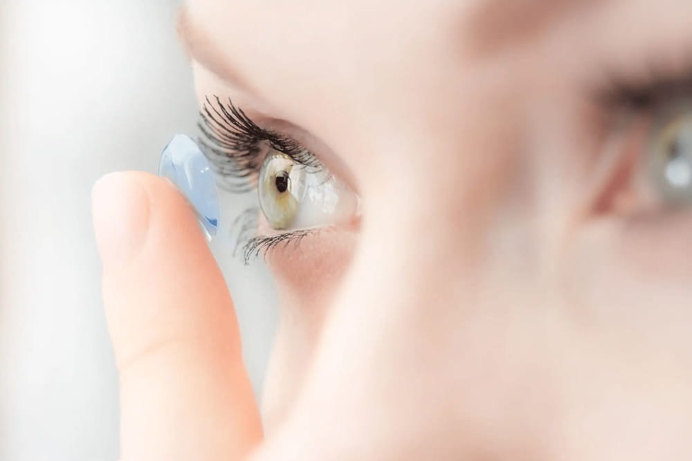 Close-up of a person inserting a contact lens into their eye.