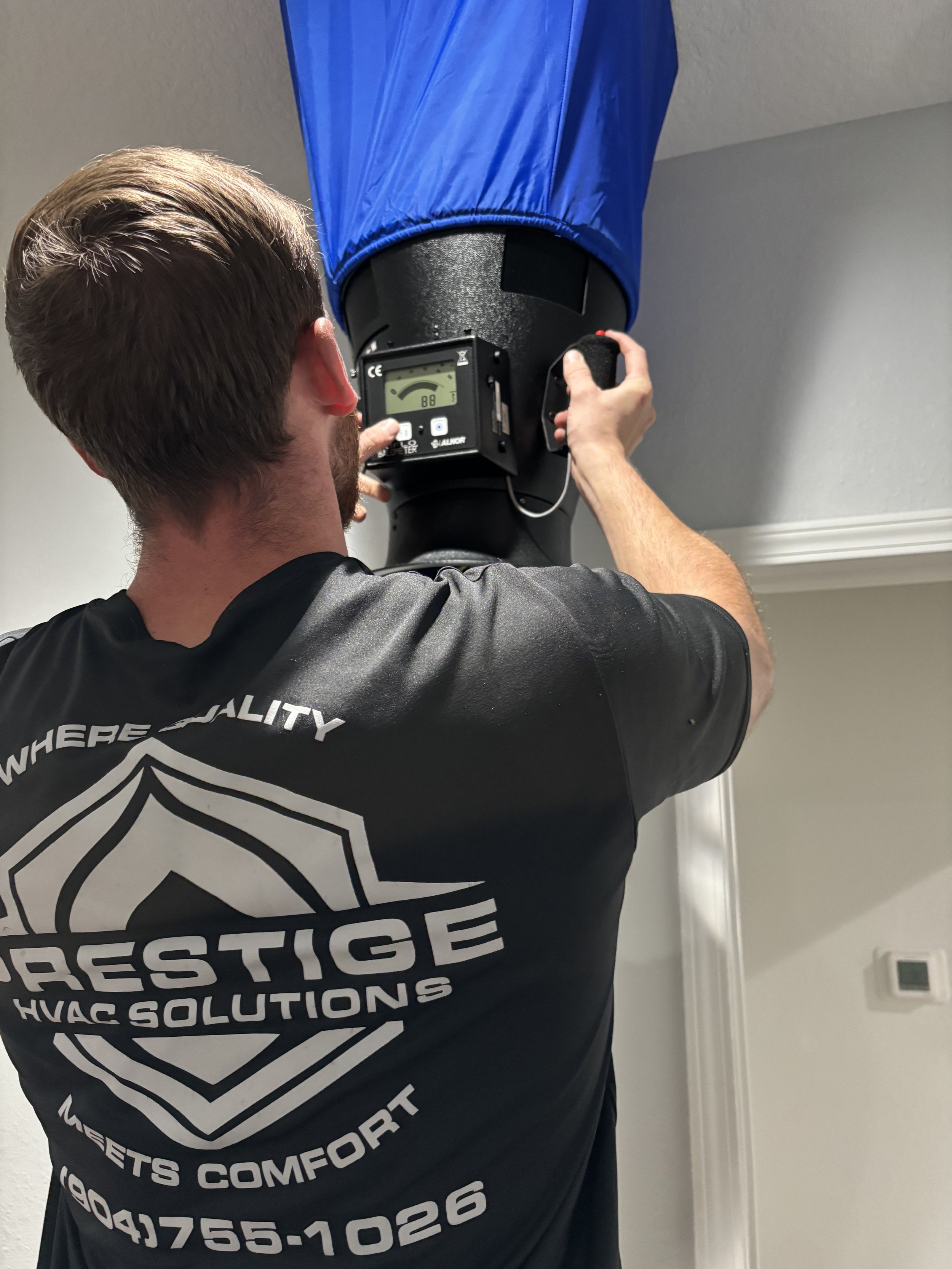 Interior view of a room showing a wall-mounted white air conditioner, a flat screen TV, a lantern-style light fixture, and a window with an arched top and curtains.