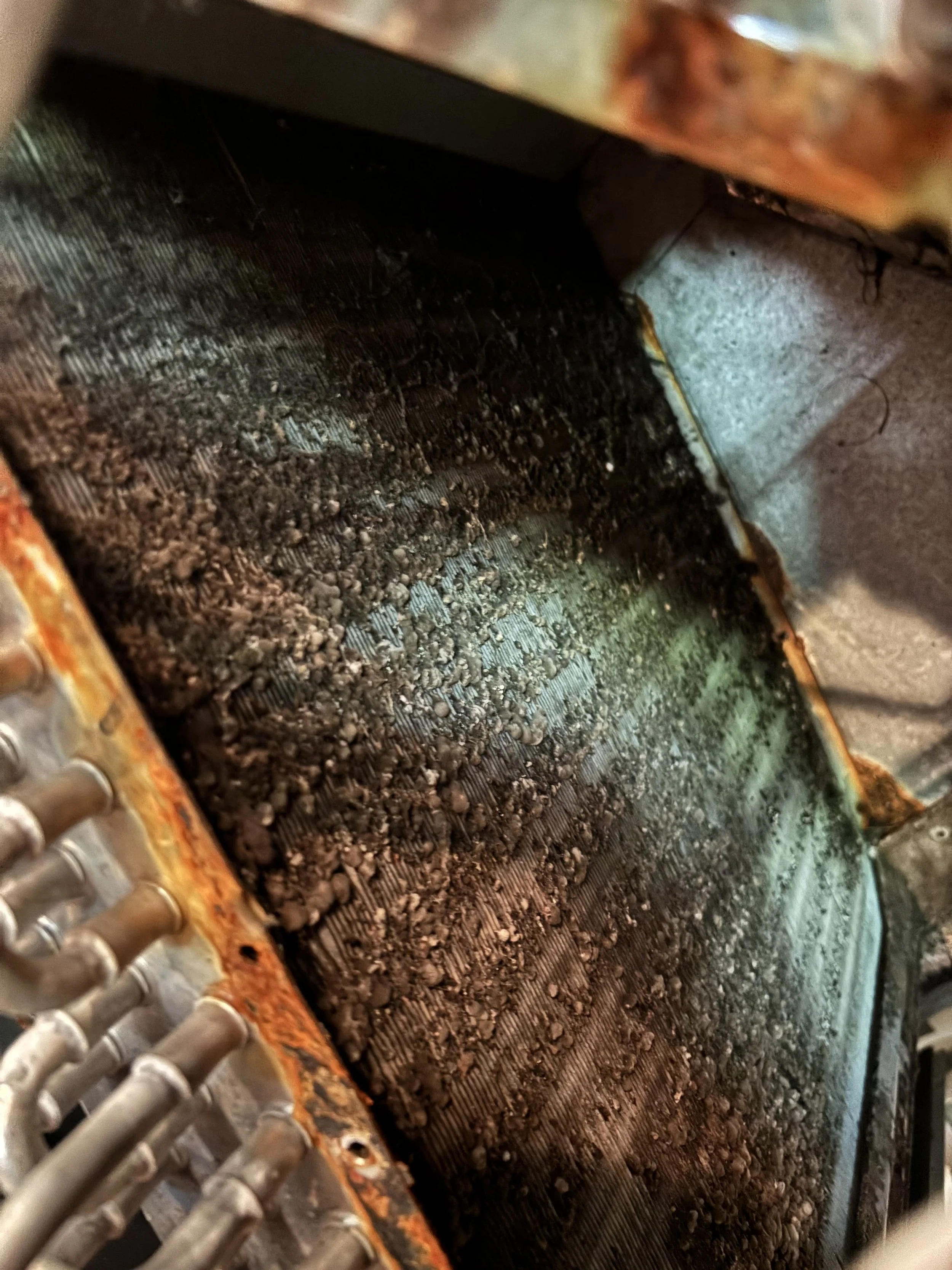 An HVAC furnace installed in an attic space surrounded by unfinished wooden framing and electrical wiring.