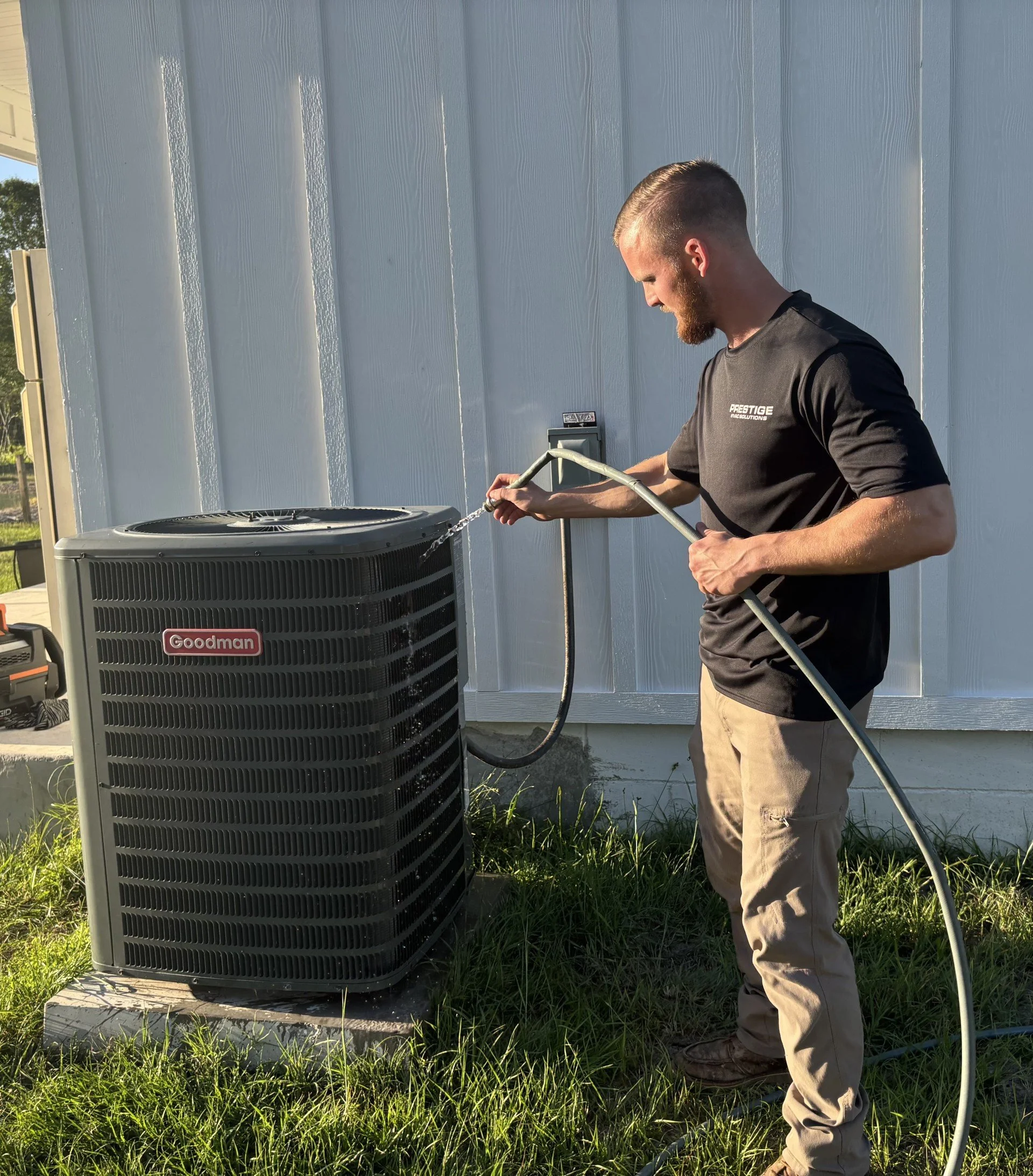 Prestige HVAC Solutions technician servicing an outdoor air conditioning system