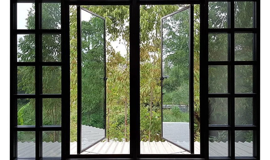 Open glass doors leading to a view of green trees outside, framed by black windowpanes.