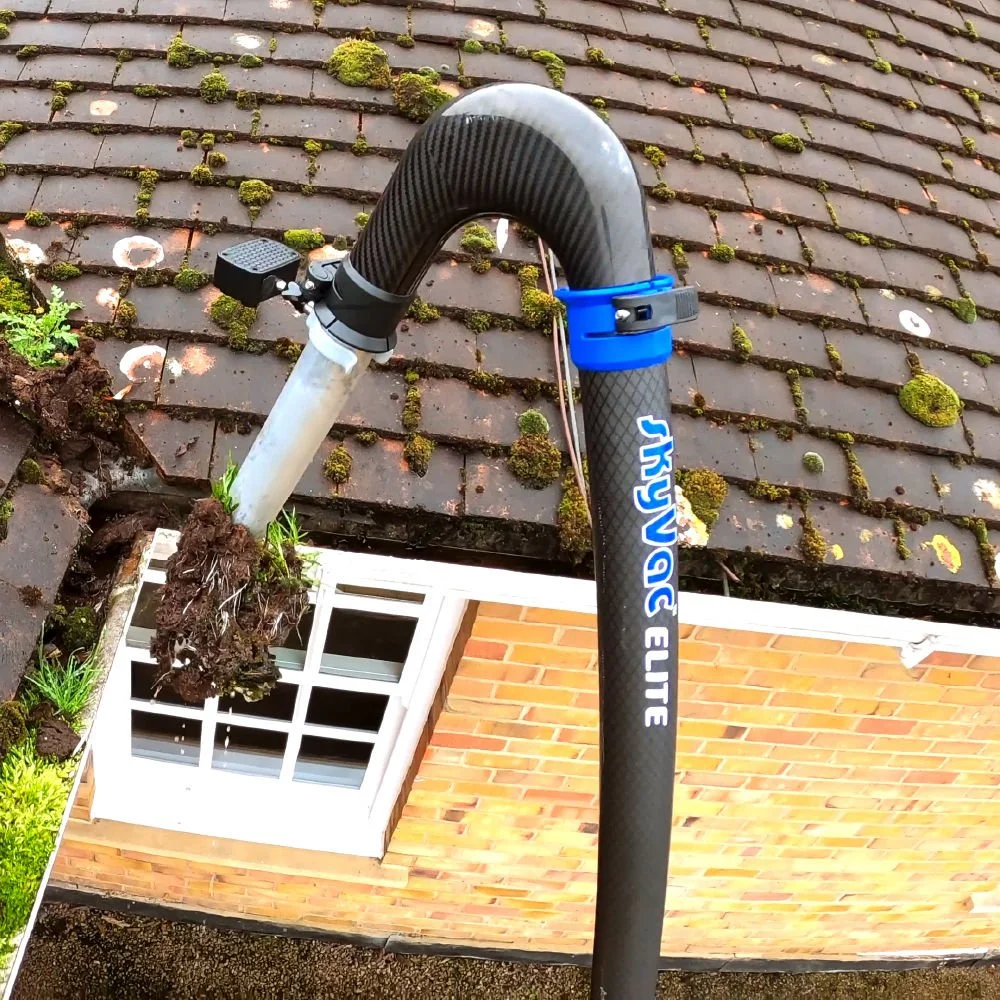 A gutter with dirt, leaves and moss being cleaning using SkyVac gutter cleaning vacuum.
