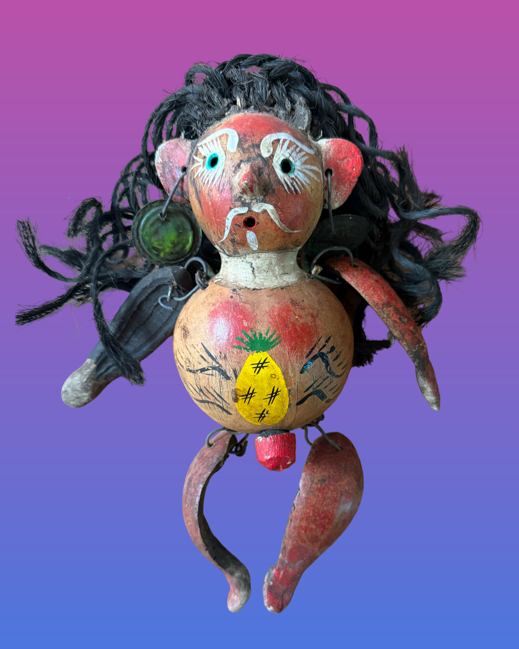 Colorful mask with human face and fish-like features, including a green scaled body, red fins, and a face with painted blue eyes, eyebrows, and lips.