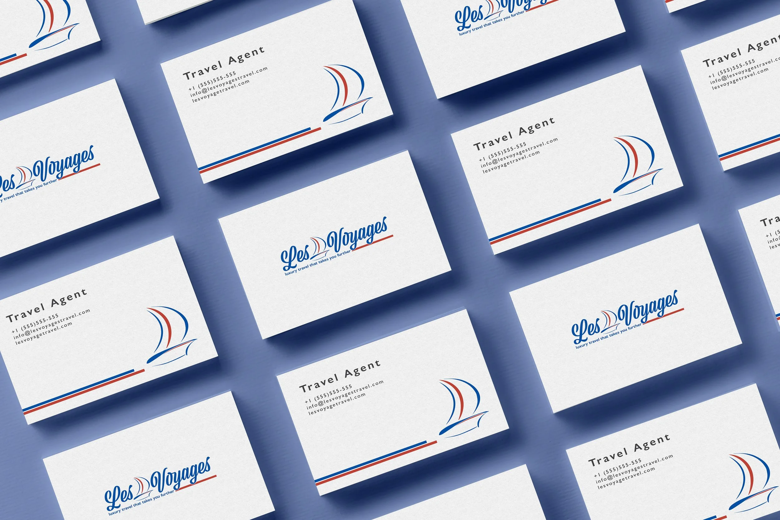 Business cards for a travel agency called Les Voyages with a logo of a sailboat in red and blue, arranged on a blue background.