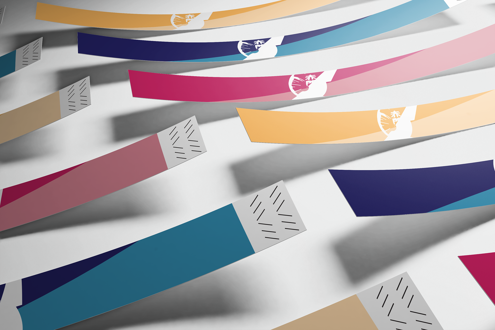 Colorful paper wristbands with a white emblem, casting shadows on a white surface.
