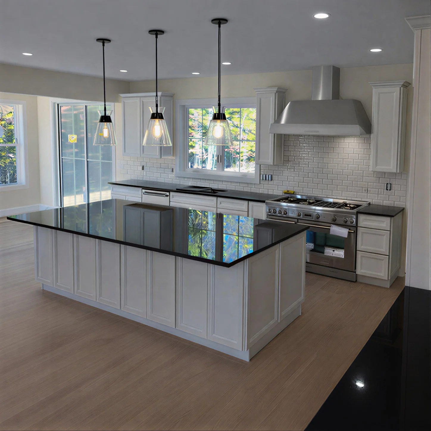 Modern kitchen with white cabinetry, black countertops, a large island, stainless steel stove, white subway tile backsplash, and pendant lighting, with windows showing greenery outside.
