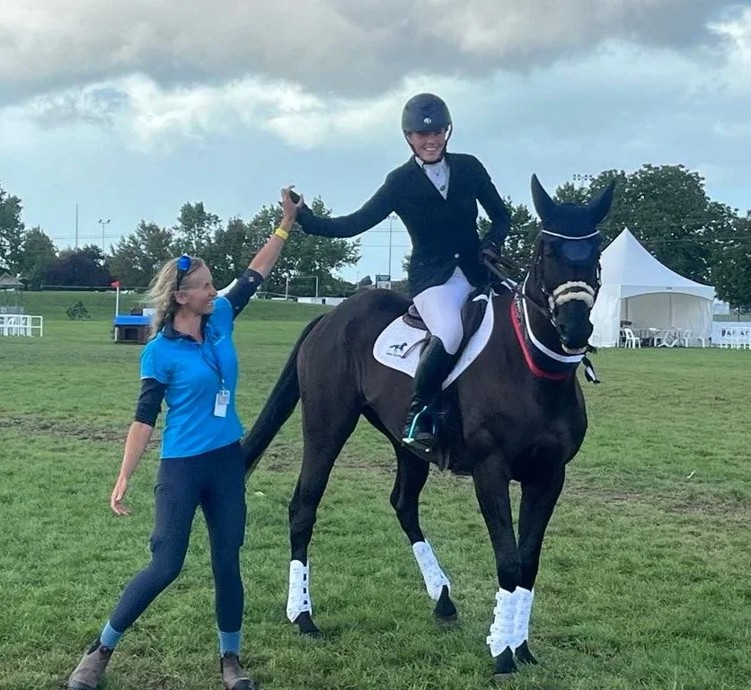 Helen the physio and female rider on black horse high five after successful competition