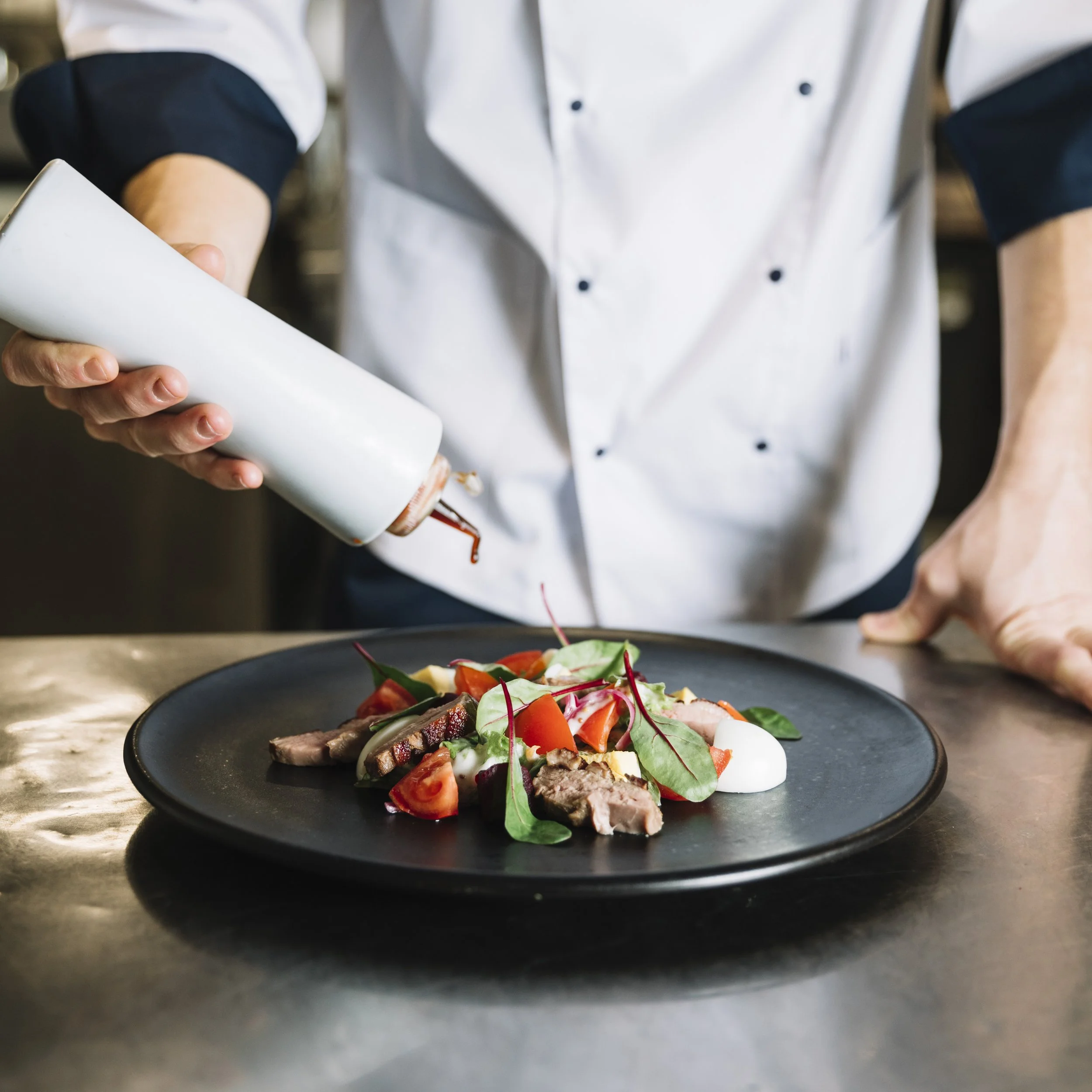 cook-pouring-sauce-plate-with-salad.jpg
