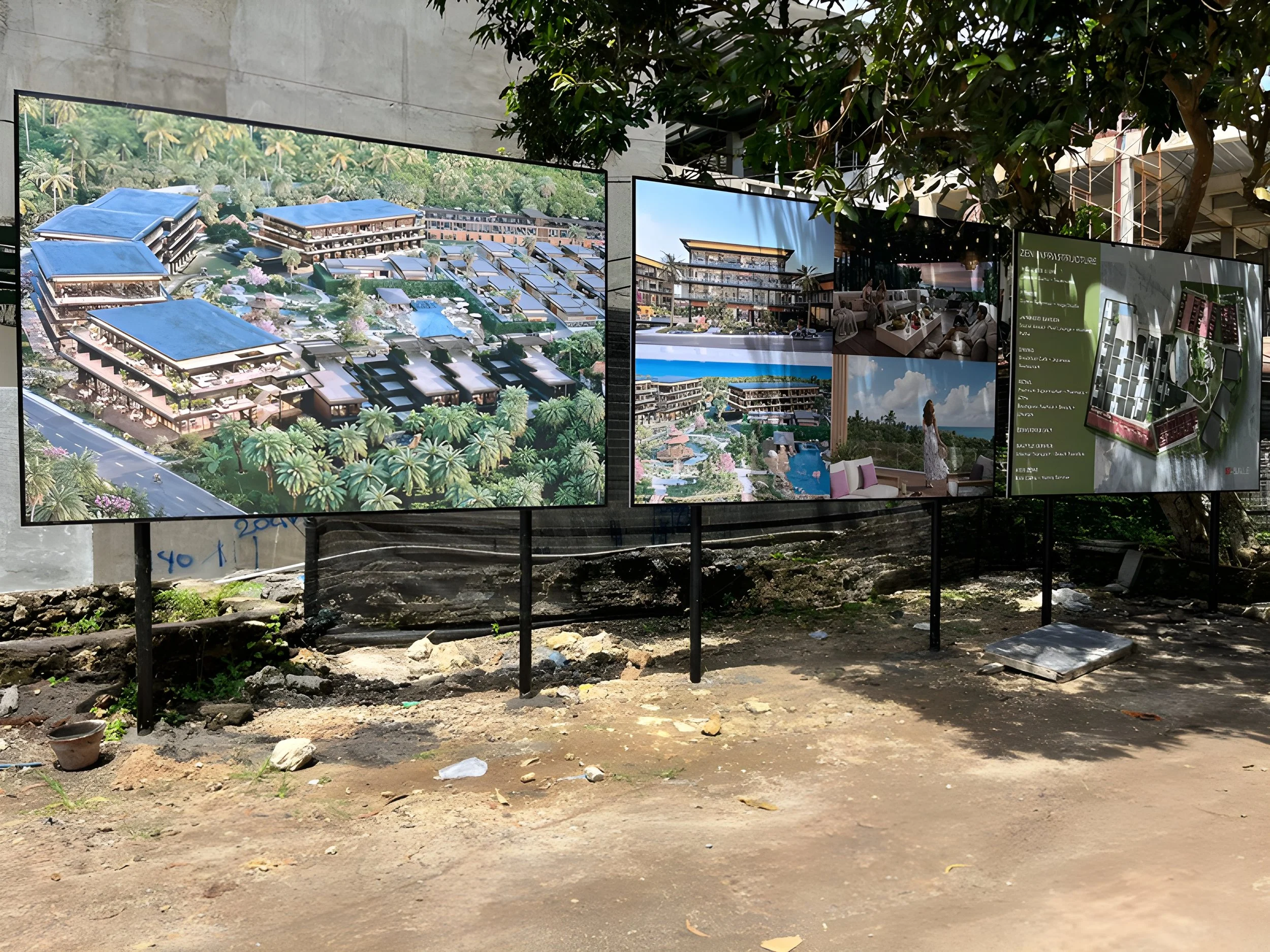 Outdoor display of architectural designs and renderings for a large resort or residential complex, with trees and construction site in the background.