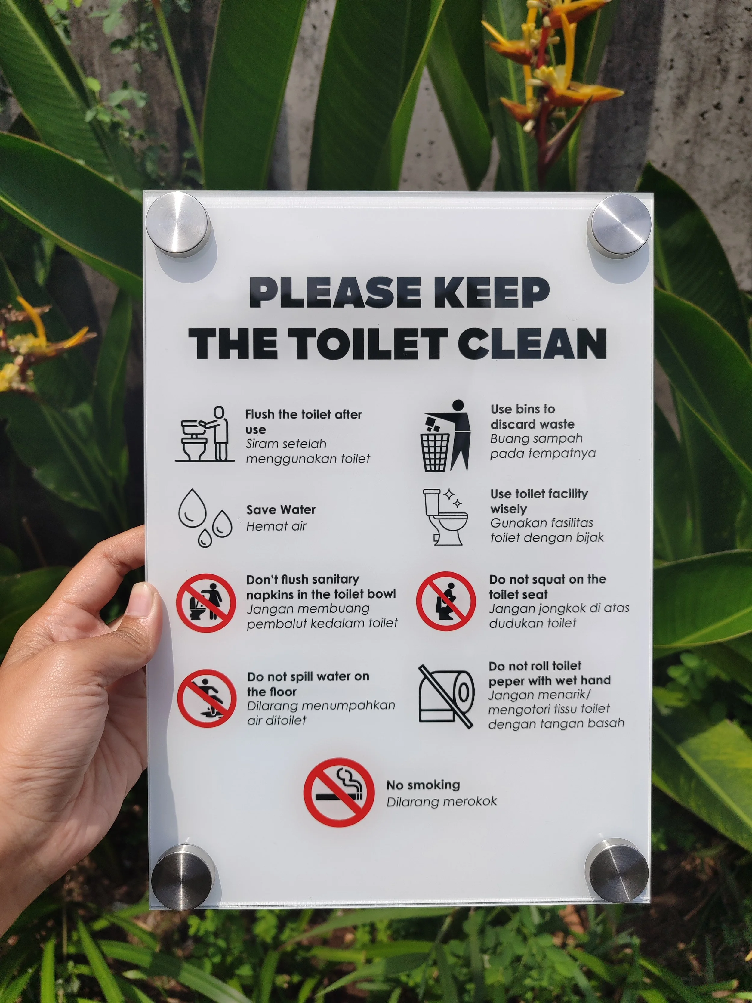 A white sign with bathroom rules including instructions to flush the toilet, save water, use bins to discard waste, use the toilet facility wisely, avoid flushing sanitary napkins, not to squat on the toilet seat, not to roll toilet paper with hands,