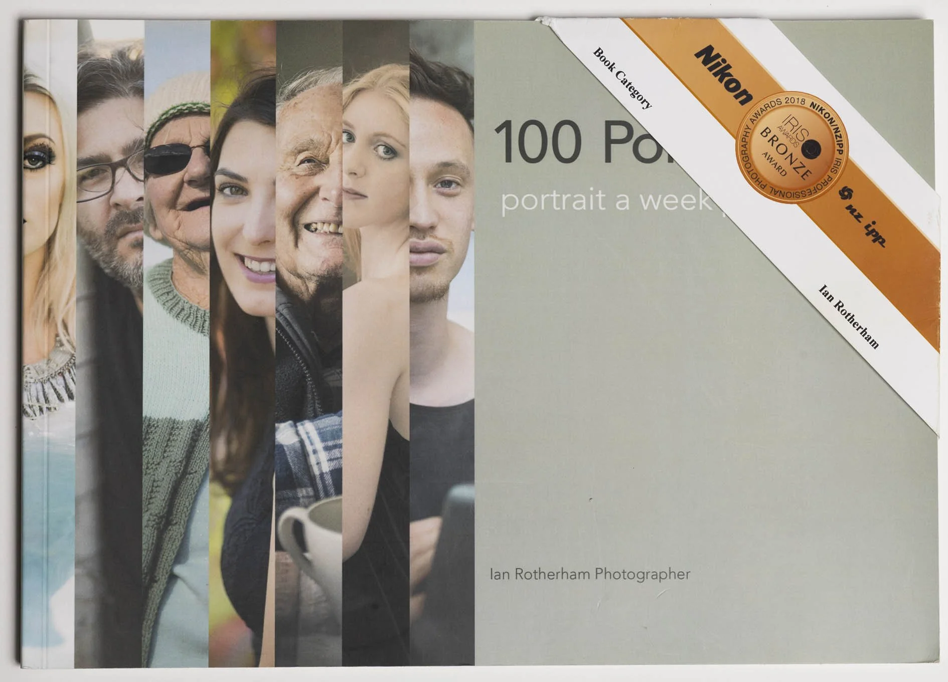 A book cover titled "100 Portraits, portrait a week" by Ian Rotherham, featuring a collage of diverse people's faces and a green background with a white and orange diagonal banner in the top right corner, which includes the Nikon logo and an award seal.