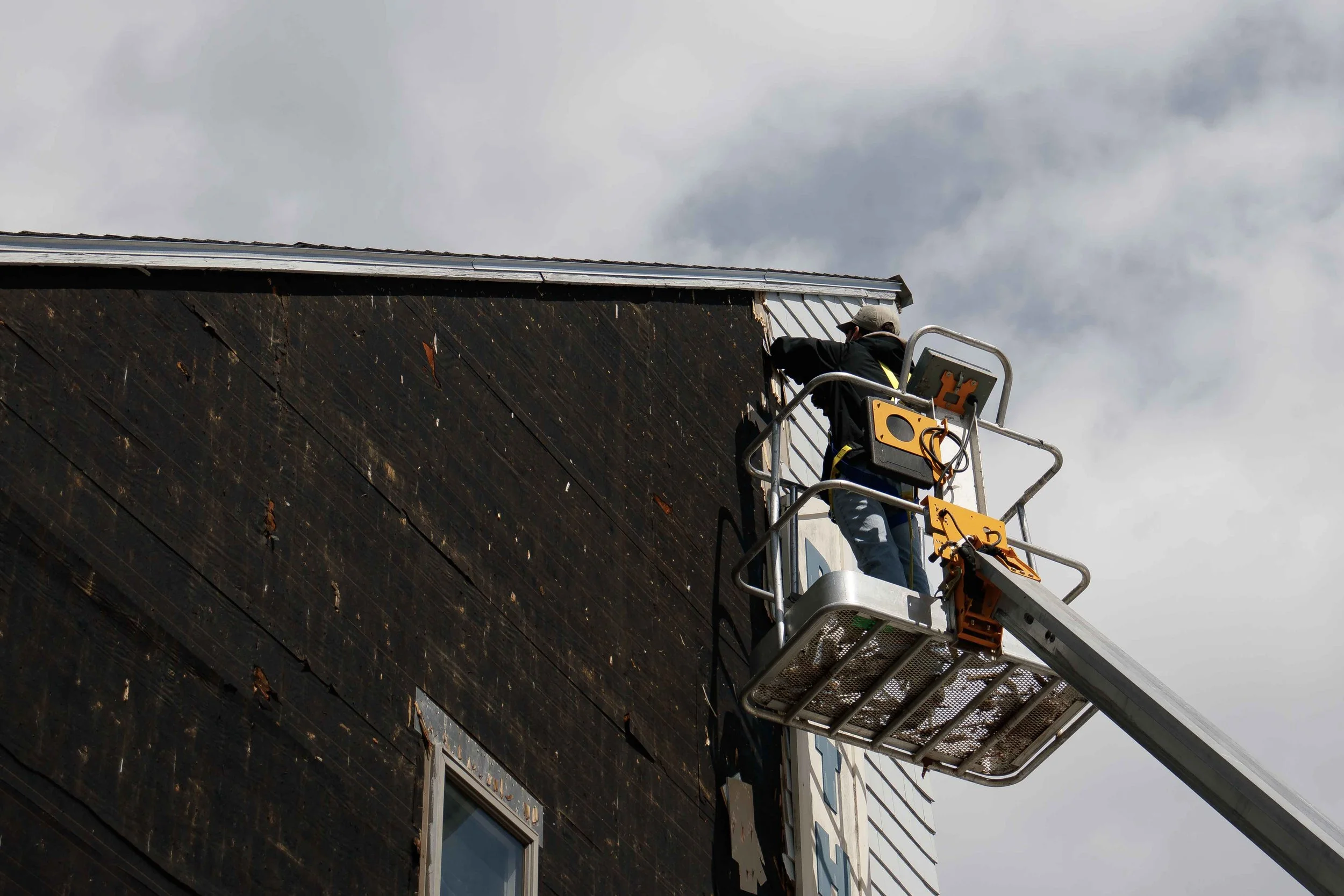 a carpenter removing cedar siding