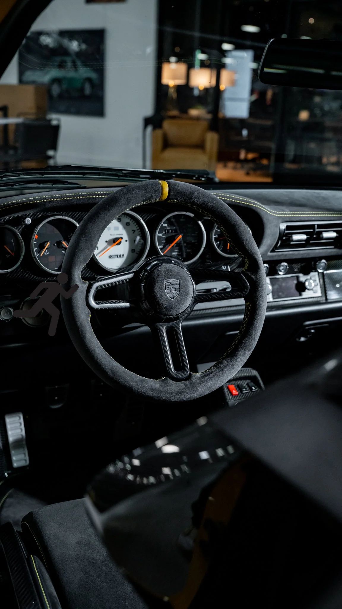 Interior of a Porsche sports car with black dashboard, racing-style steering wheel, and analog gauges.