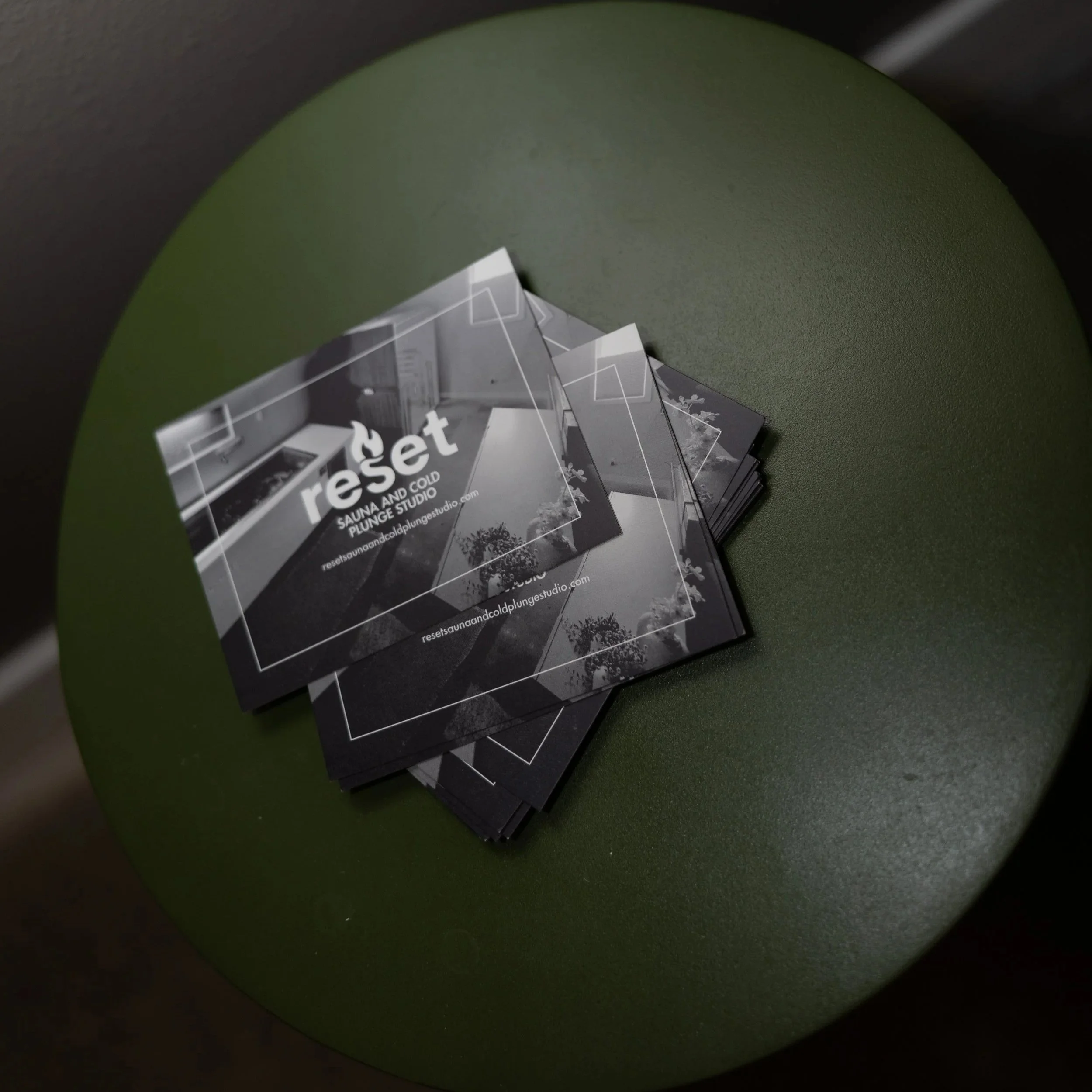 A stack of black and white business cards with the text "reset" on a green circular surface.