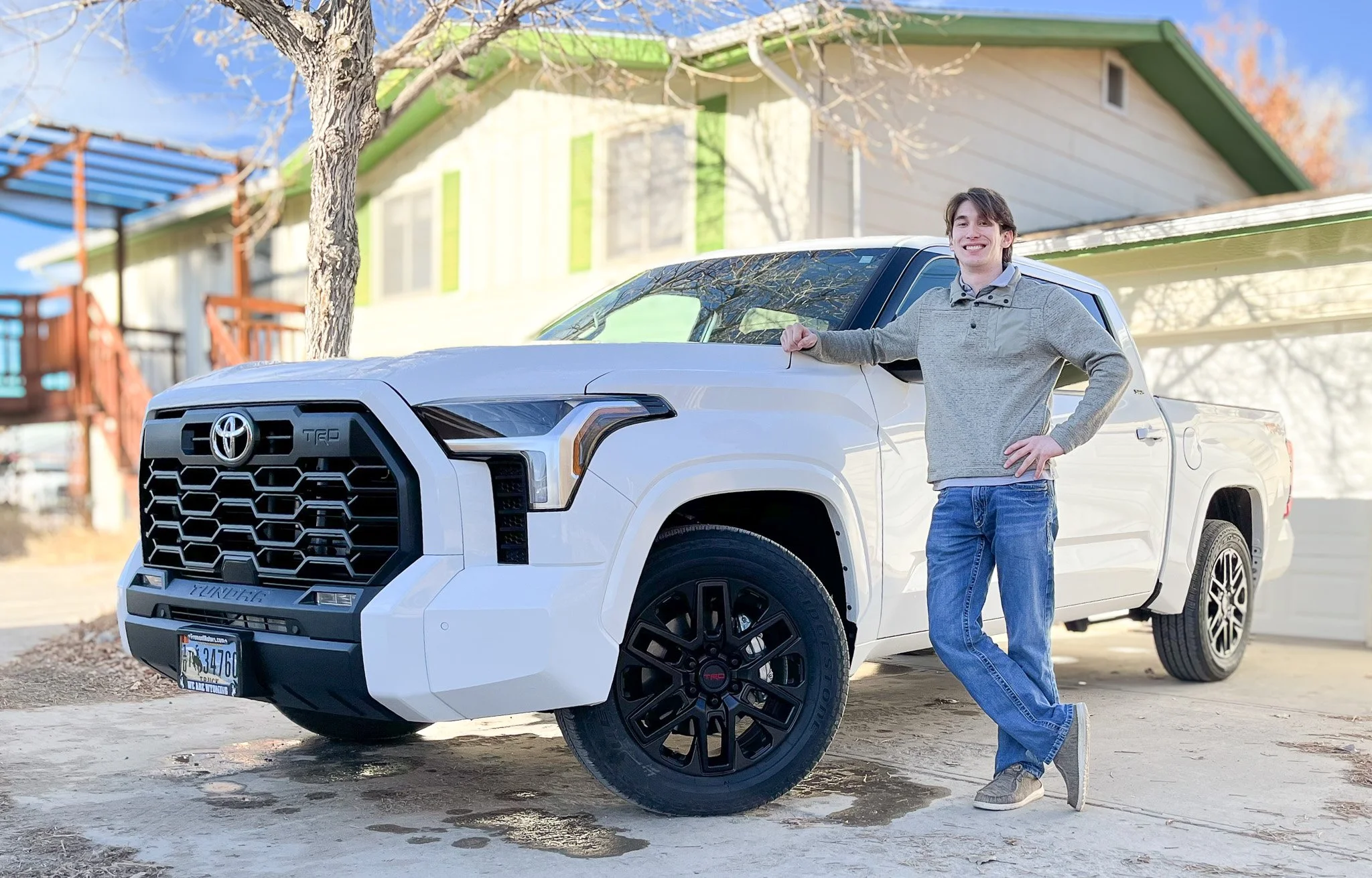 A young man leaning on a white Toyota Tundra pickup truck, standing on a driveway in Lander, Wyoming.