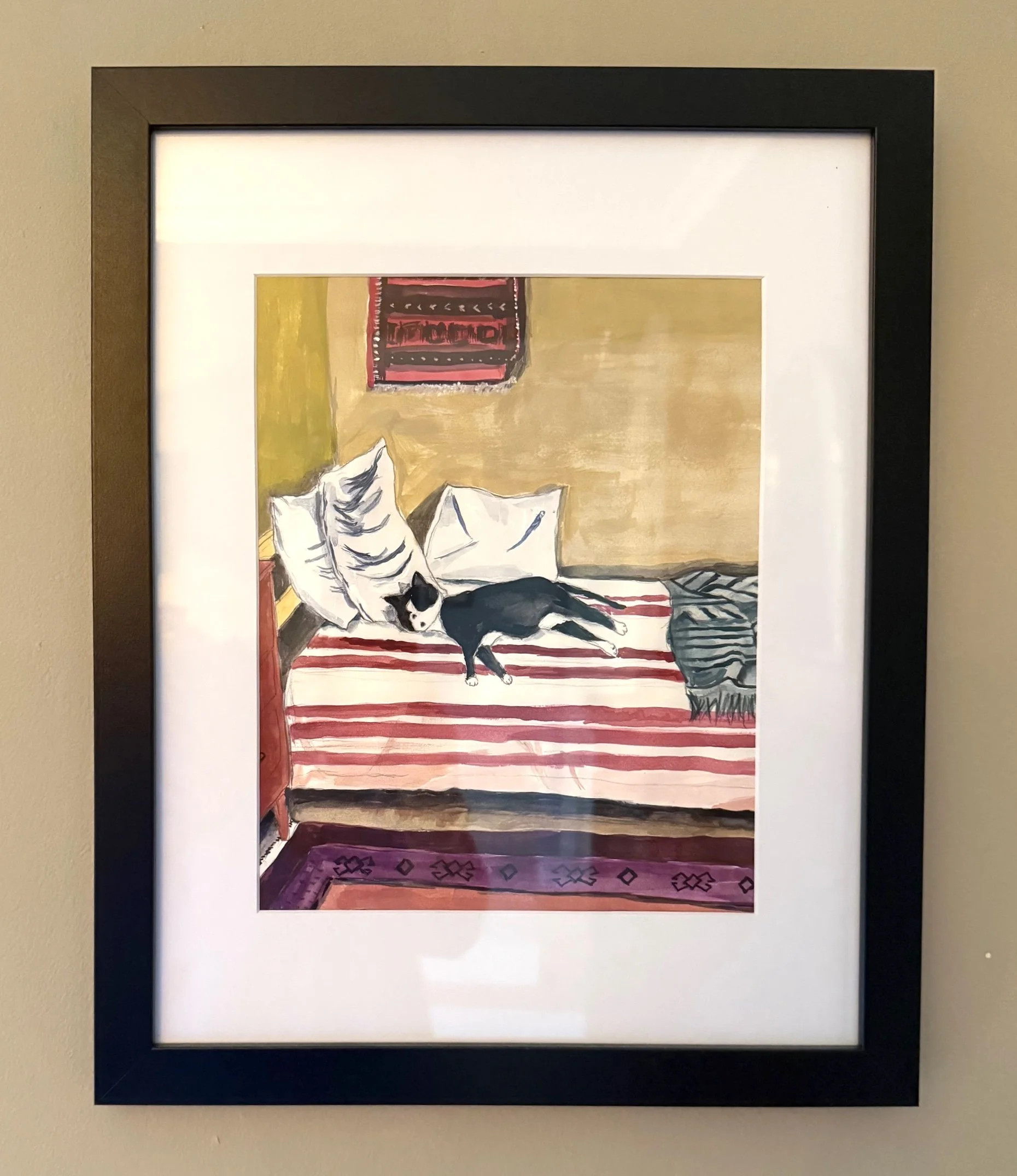Painting of a black and white cat lying on a striped red, pink, and white bed with pillows, a blanket, a colorful wall hanging, and a patterned rug in the room.