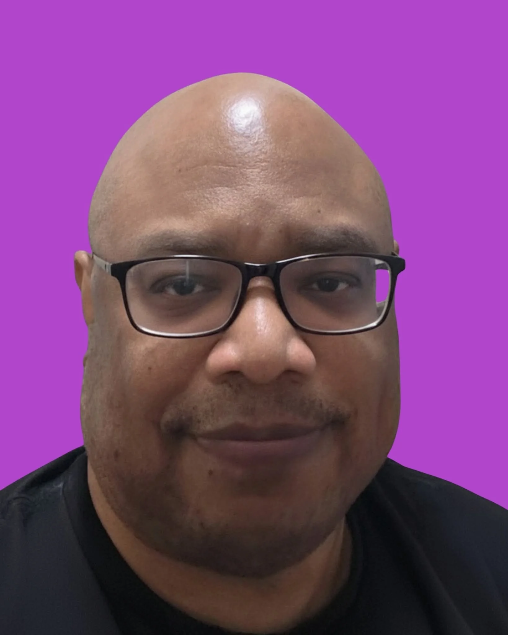 Close-up portrait of a smiling man with glasses and a bald head against a purple background.