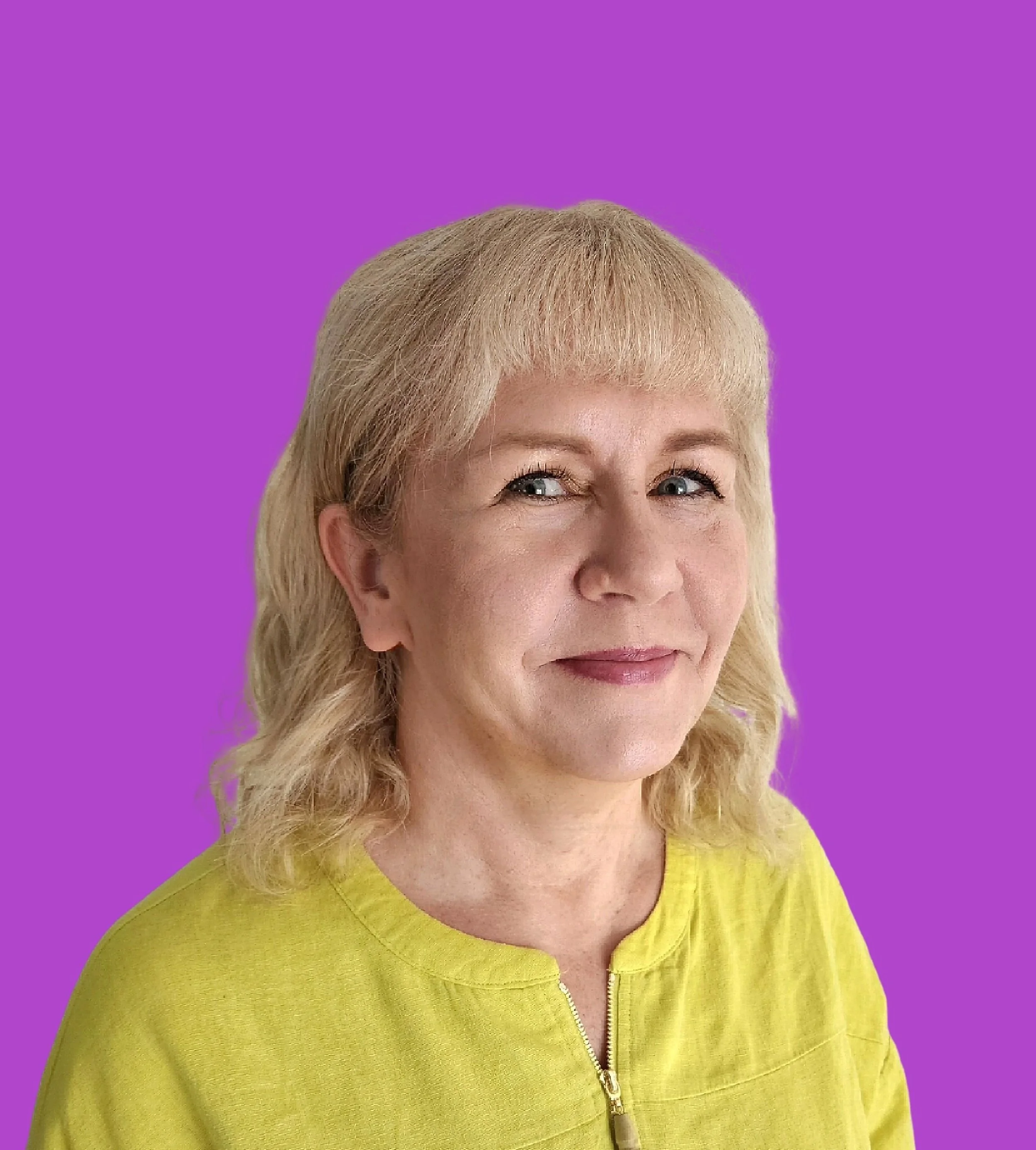 A woman with blonde hair and blue eyes wearing a yellow top stands against a purple background.
