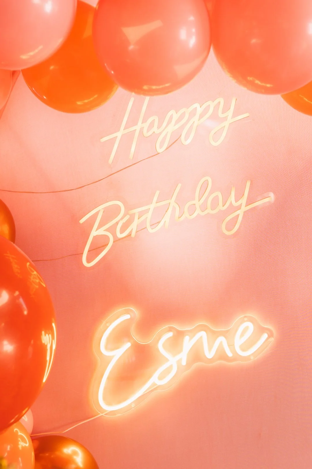 Decorative pink background with a neon sign that reads "Enjoy" and a message that says "Happy Birthday" surrounded by orange balloons.