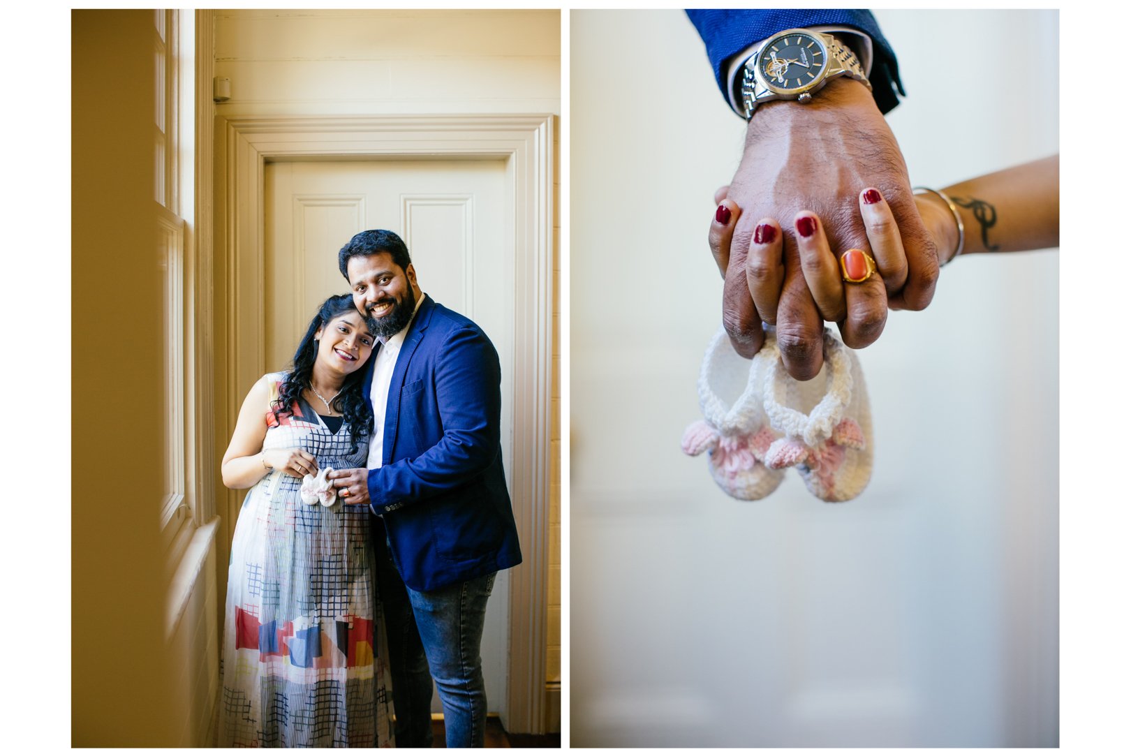 A joyful South Asian couple, woman in a colorful dress and man in a blue blazer, standing together in a warmly lit interior. The woman holds small baby booties, and the man is smiling happily. The close-up shows their hands clasped, with the woman's 
