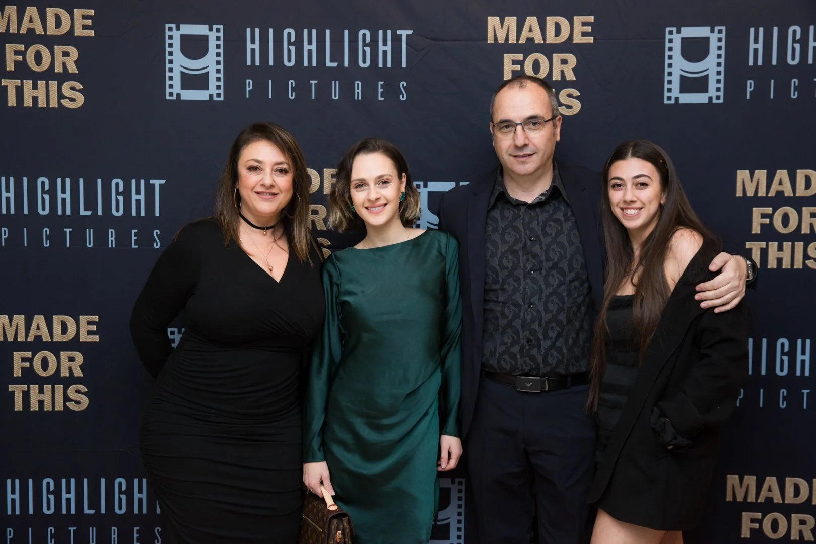 A group of four people posing together at a Premiere event. They are standing in front of a backdrop with the words 'Highlight Pictures' and 'Made for This' written repeatedly.
