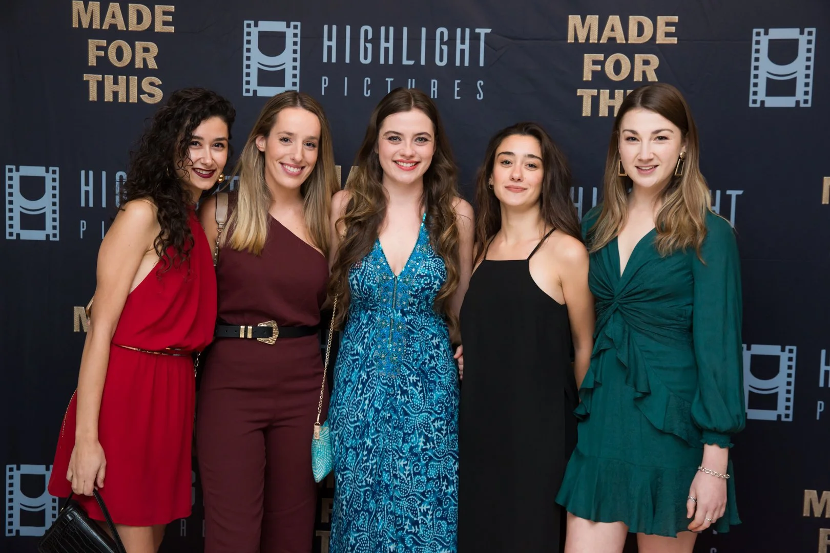 Five women dressed in formal attire standing together on a red carpet at an event with a dark blue background that has the words "Highlight Pictures" and "Made for This" printed on it.