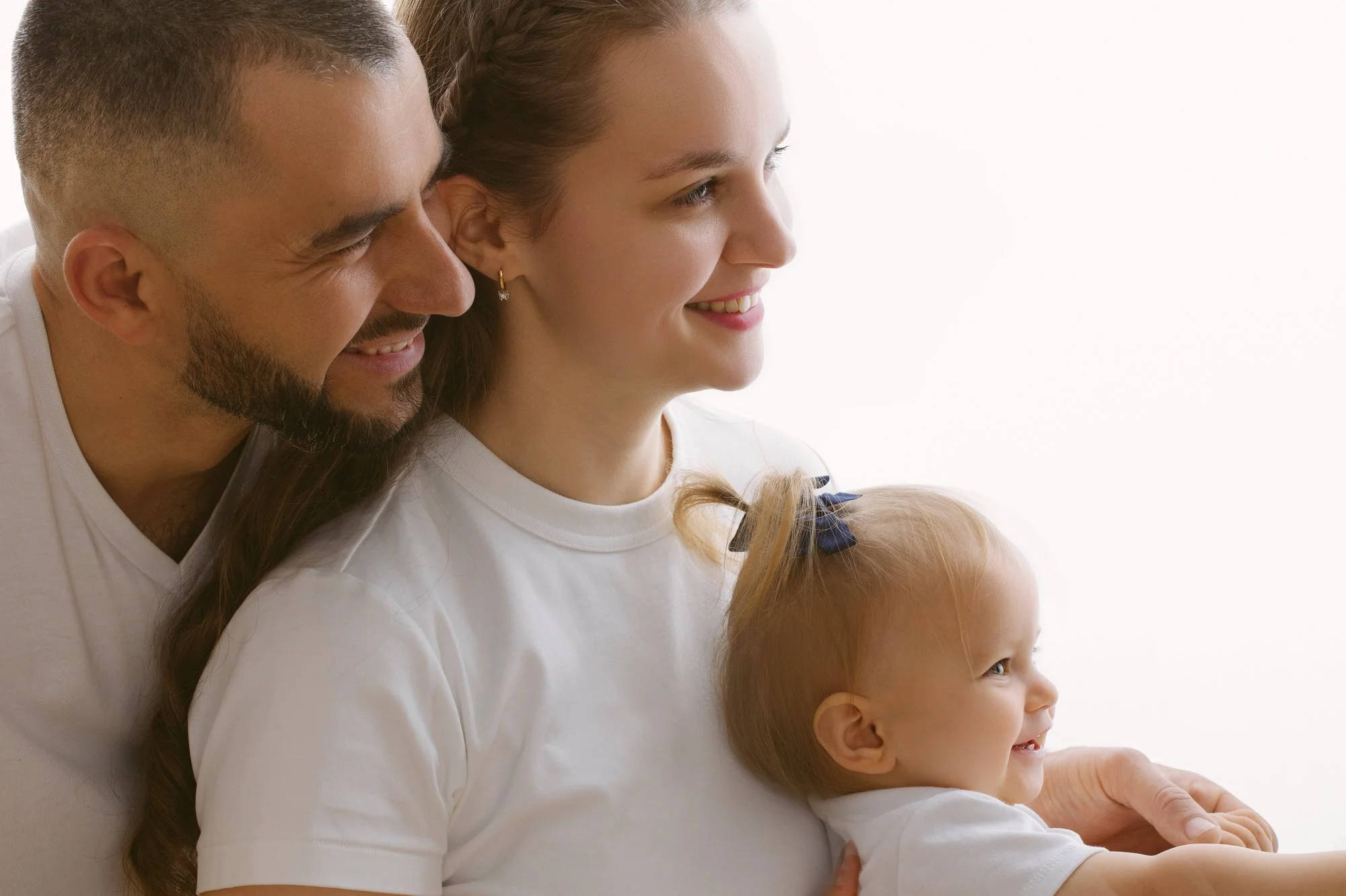 A happy family of three: a man, woman, and young girl, smiling together, close-up portrait.