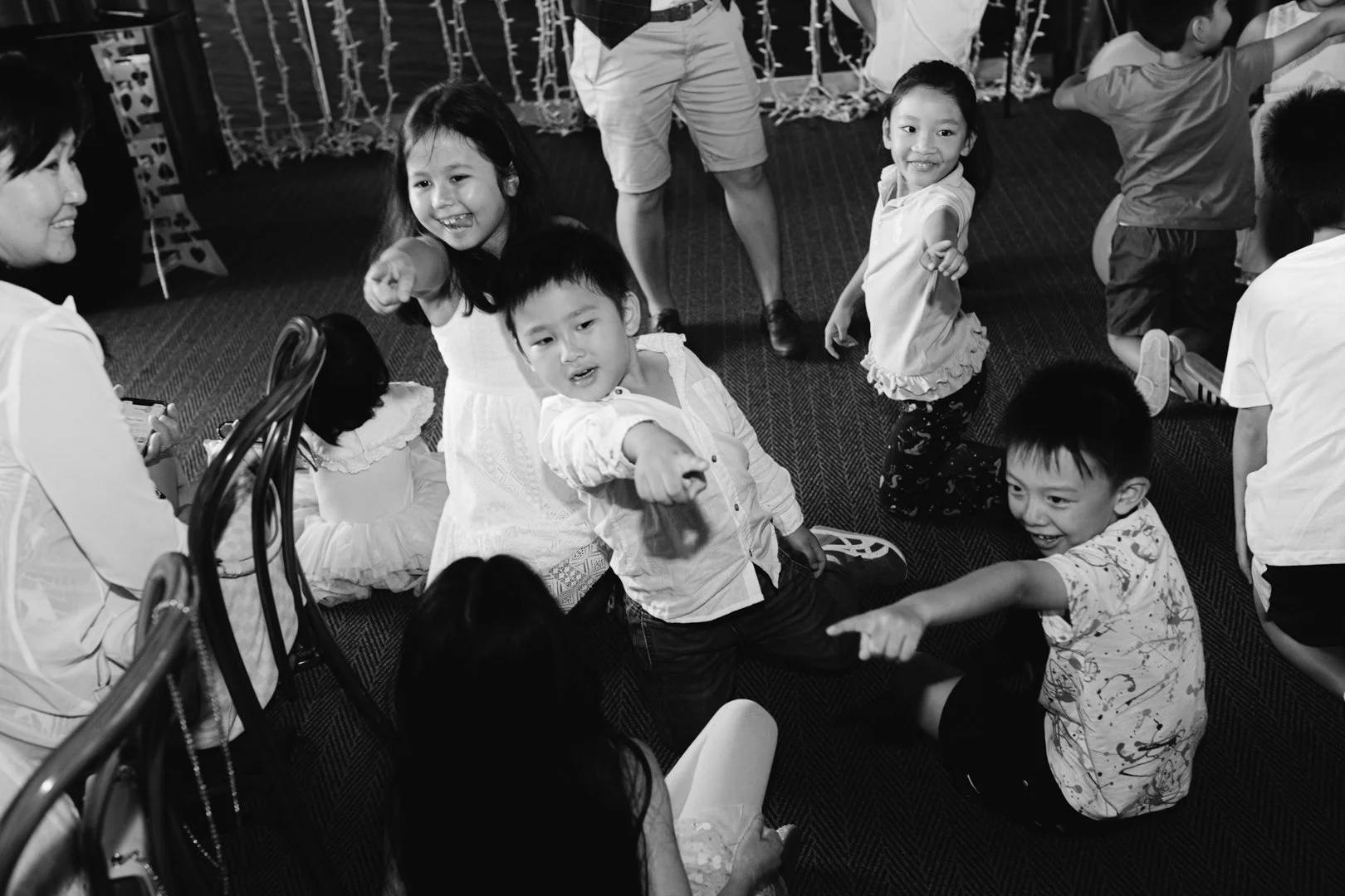 Group of children and adults playing and pointing at each other at a party or celebration.