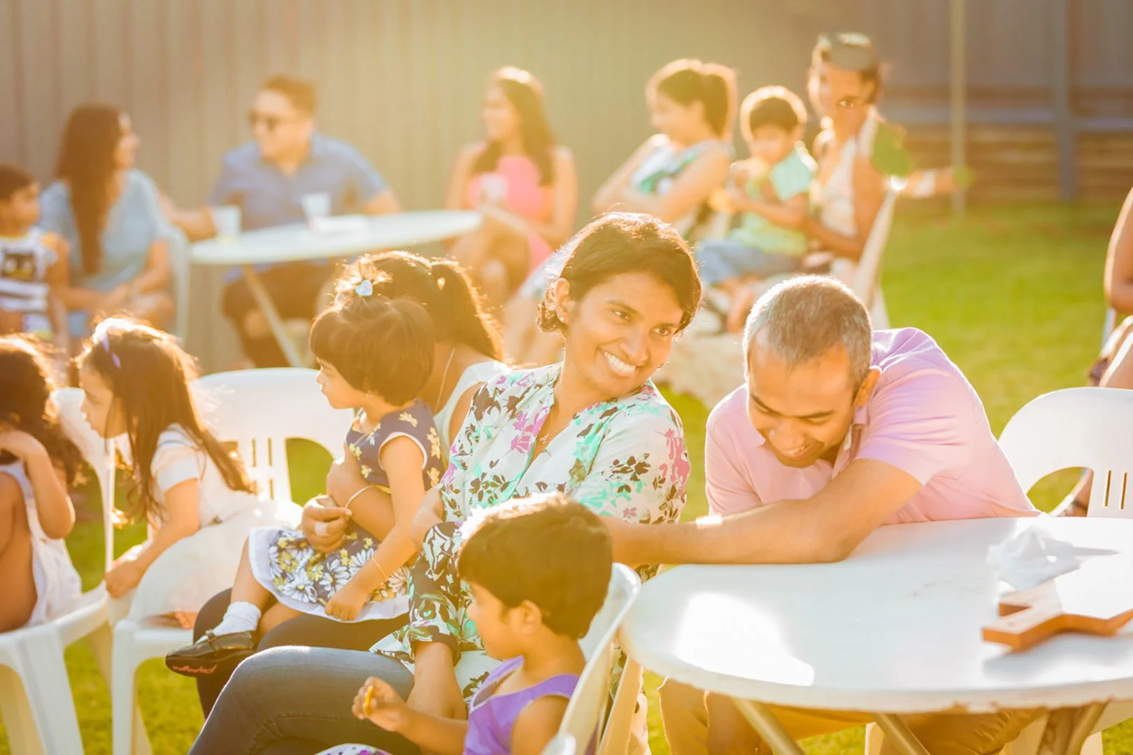 People enjoying an outdoor gathering with children and adults socializing on a sunny day.