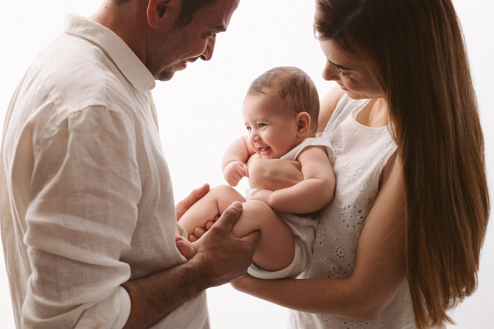 A man and woman holding a smiling baby together, sharing a loving moment.