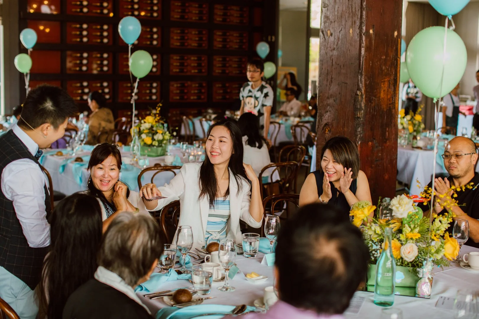 People celebrating at a decorated banquet with balloons and flowers.