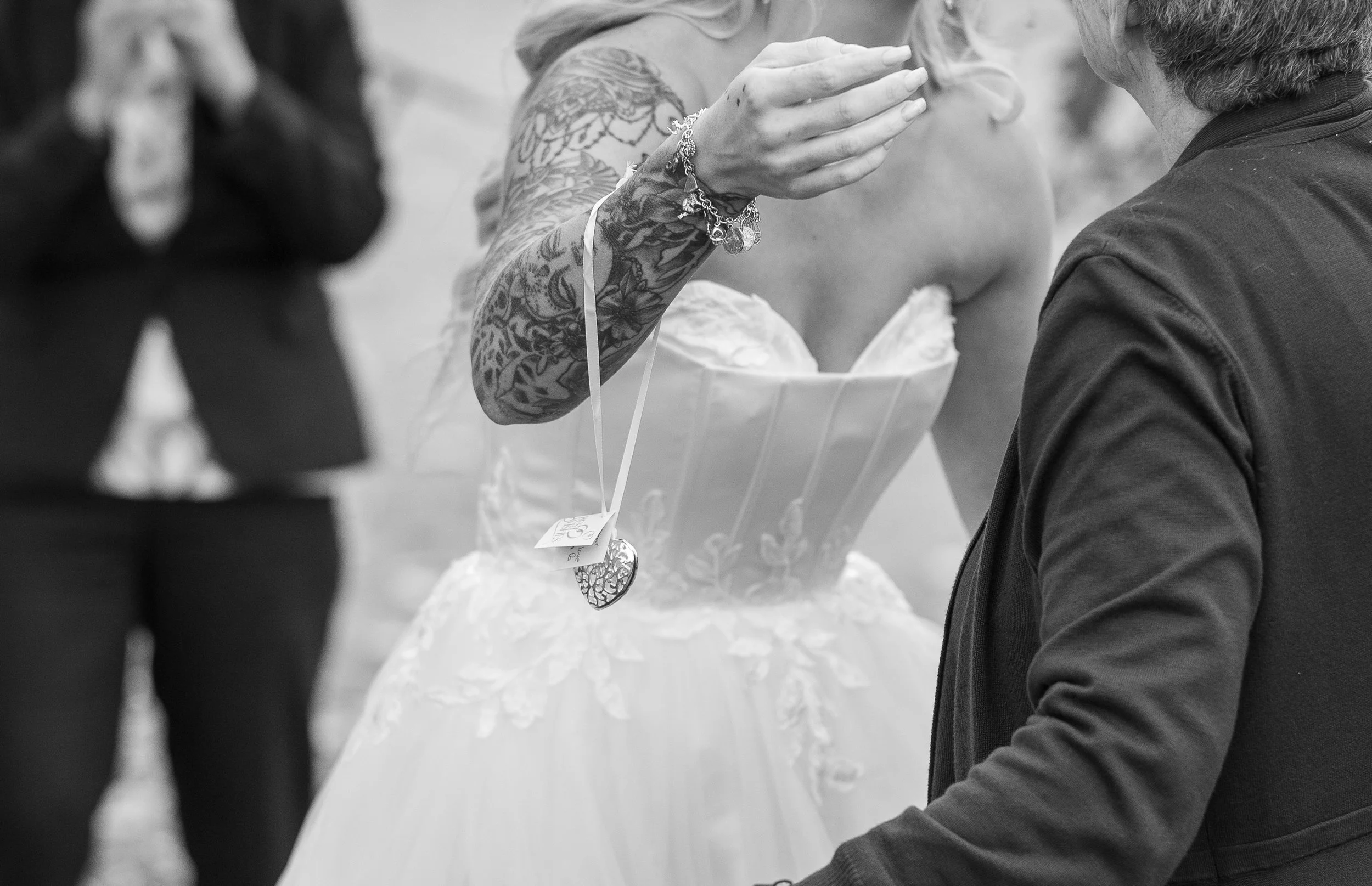 A woman with tattoos on her arm is speaking to a man while holding a large gift bag or box.