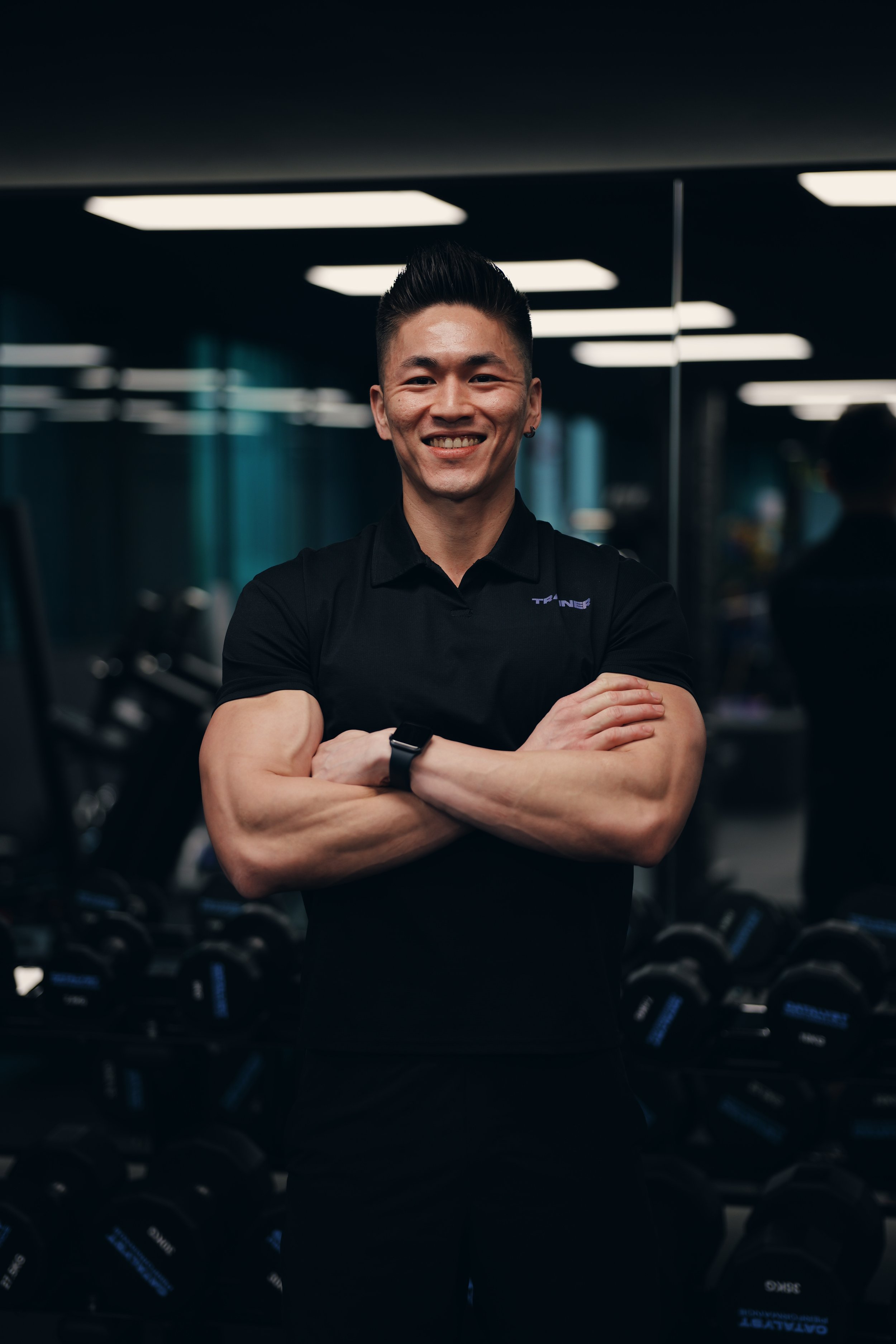 A fit young man with arms folded smiling to the camera