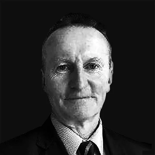 Black and white portrait of a man in a suit with a tie, facing forward against a dark background.