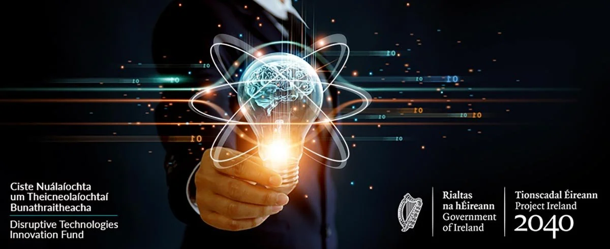 A person in a suit holding a glowing light bulb with a digital illustration of a brain and atom orbit lines above it, representing innovation. Irish government and Project Ireland 2040 logos are present along with text in Irish and English.