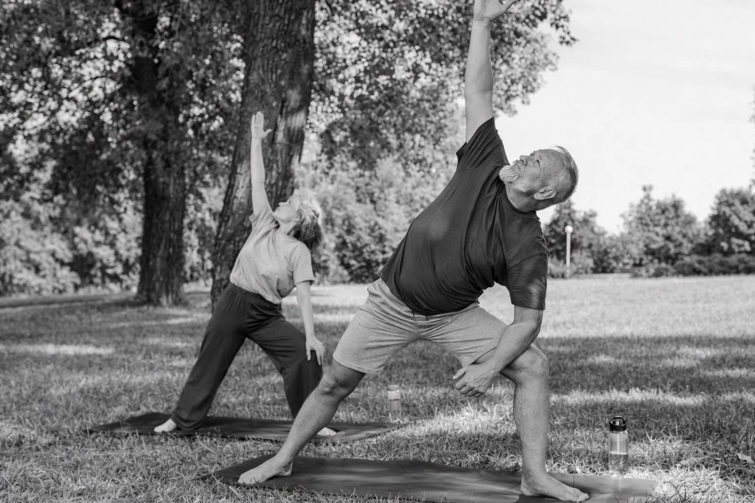 Black and white photograph of adults performing gentle stretching exercises outdoors, illustrating safe exercise in autoimmune rheumatic disease