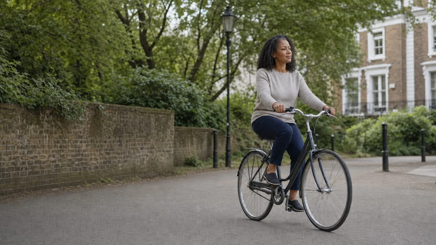 Woman cycling at a relaxed pace along a quiet leafy London street after receiving care for rheumatoid arthritis.