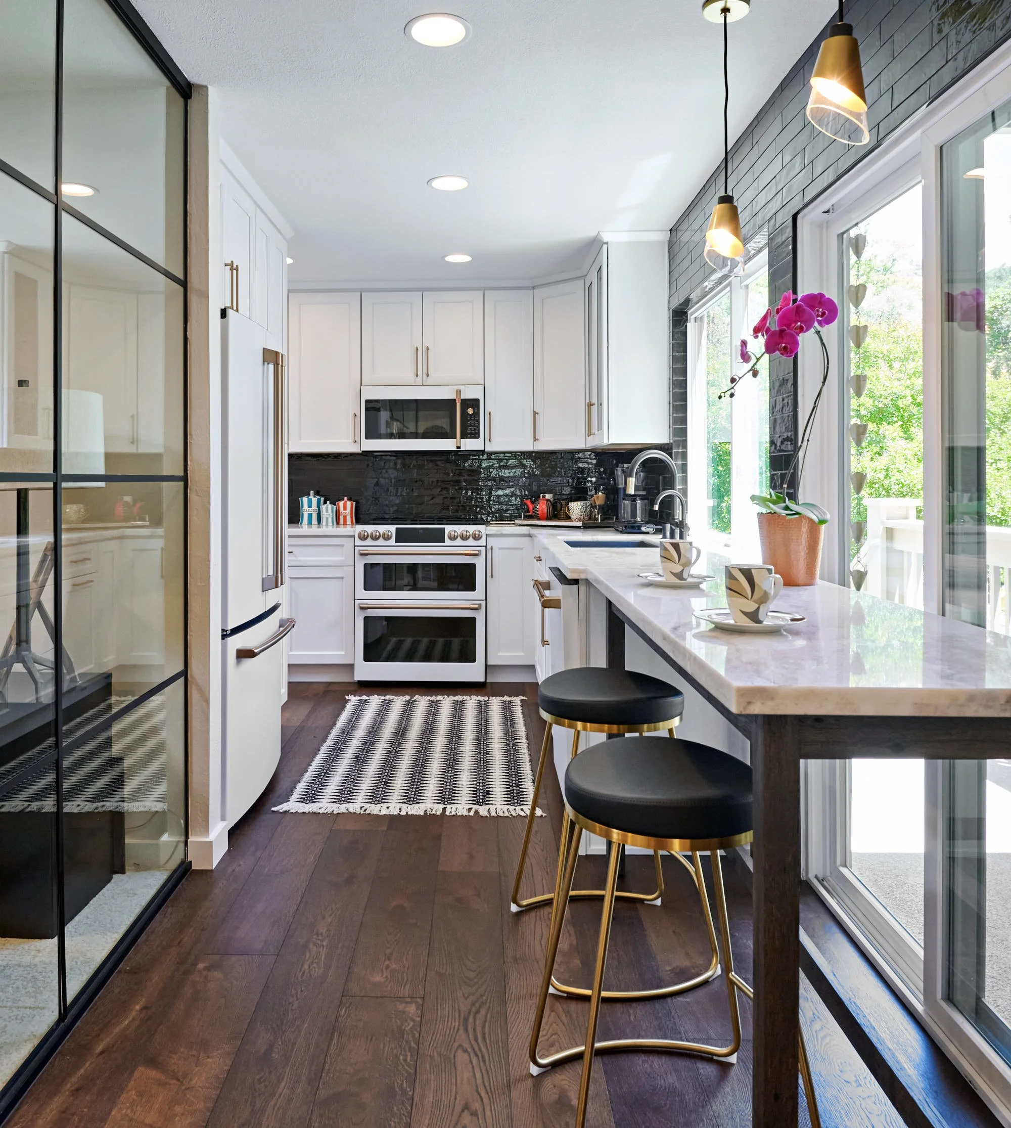 raashi-design-walnut-creek-ca-factors-in-interior-design-investment-small-modern-kitchen-with-glass-wall-large-windows-black-and-white-elegant-design.jpg