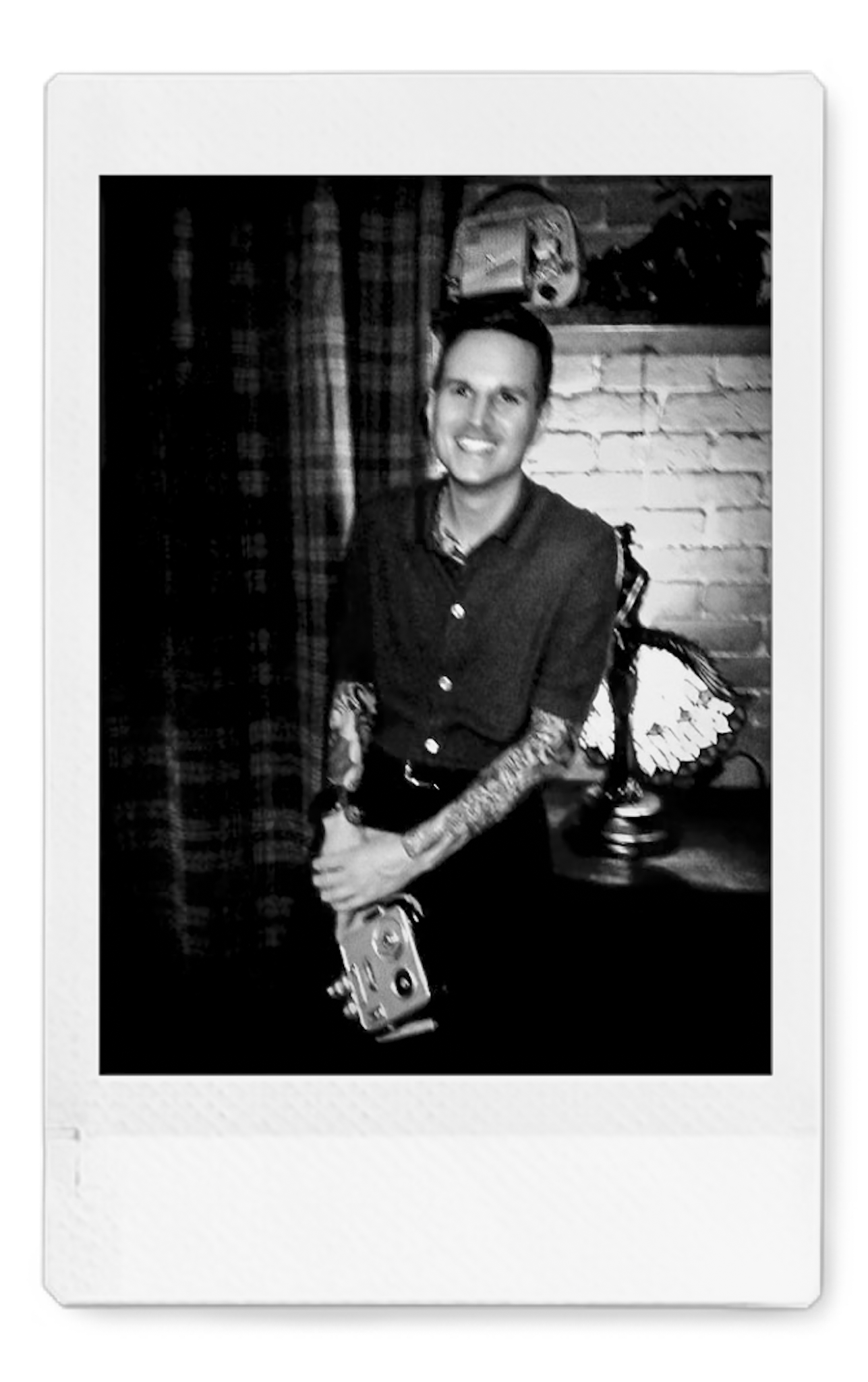 Portrait of a wedding filmmaker holding a vintage super8 film camera. Black and white polaroid.