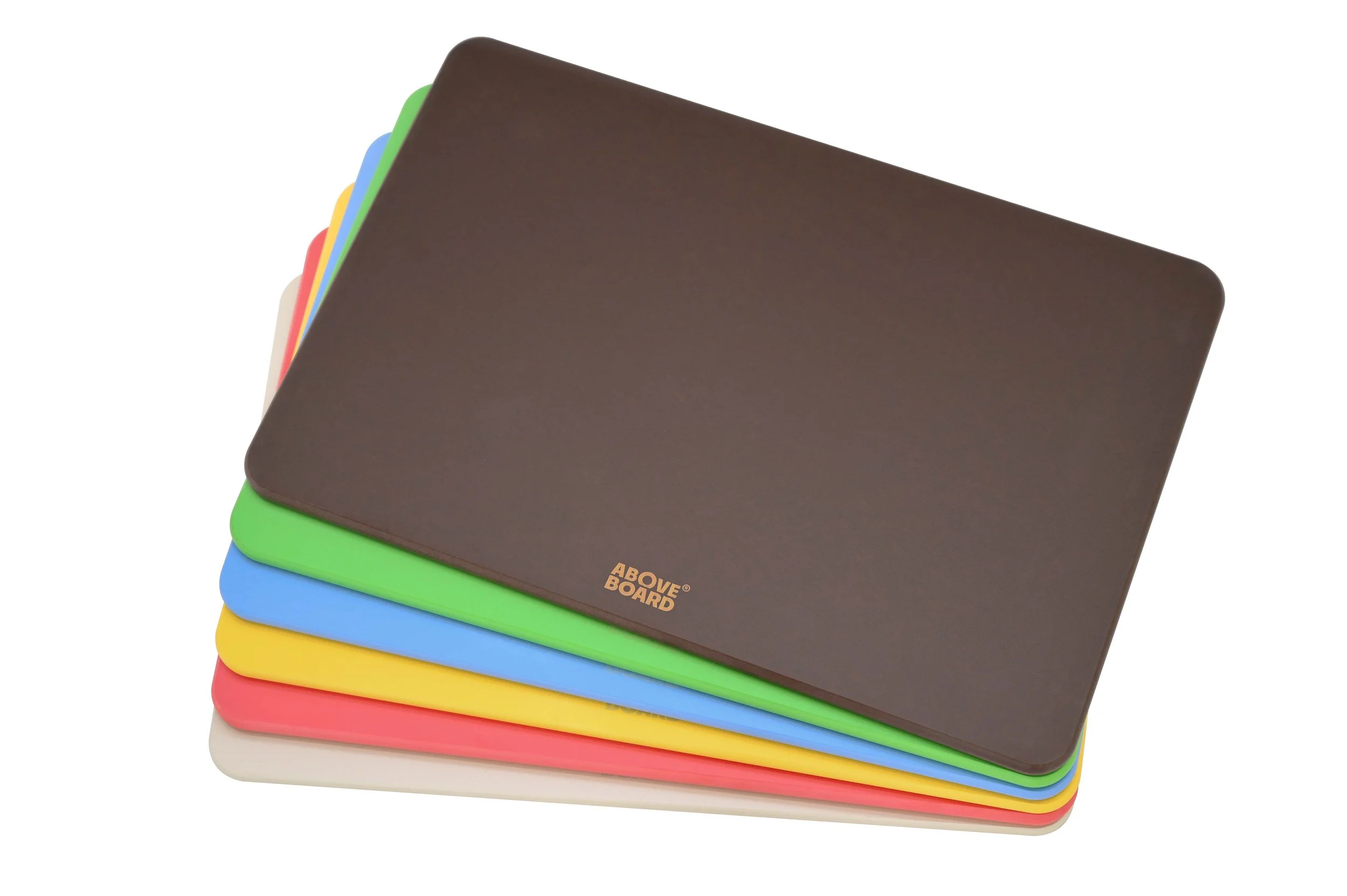 A stack of colourful wood fibre "mirco-plastic-free" cutting boards with a brown one on top labelled 'ABOVE BOARD®'.