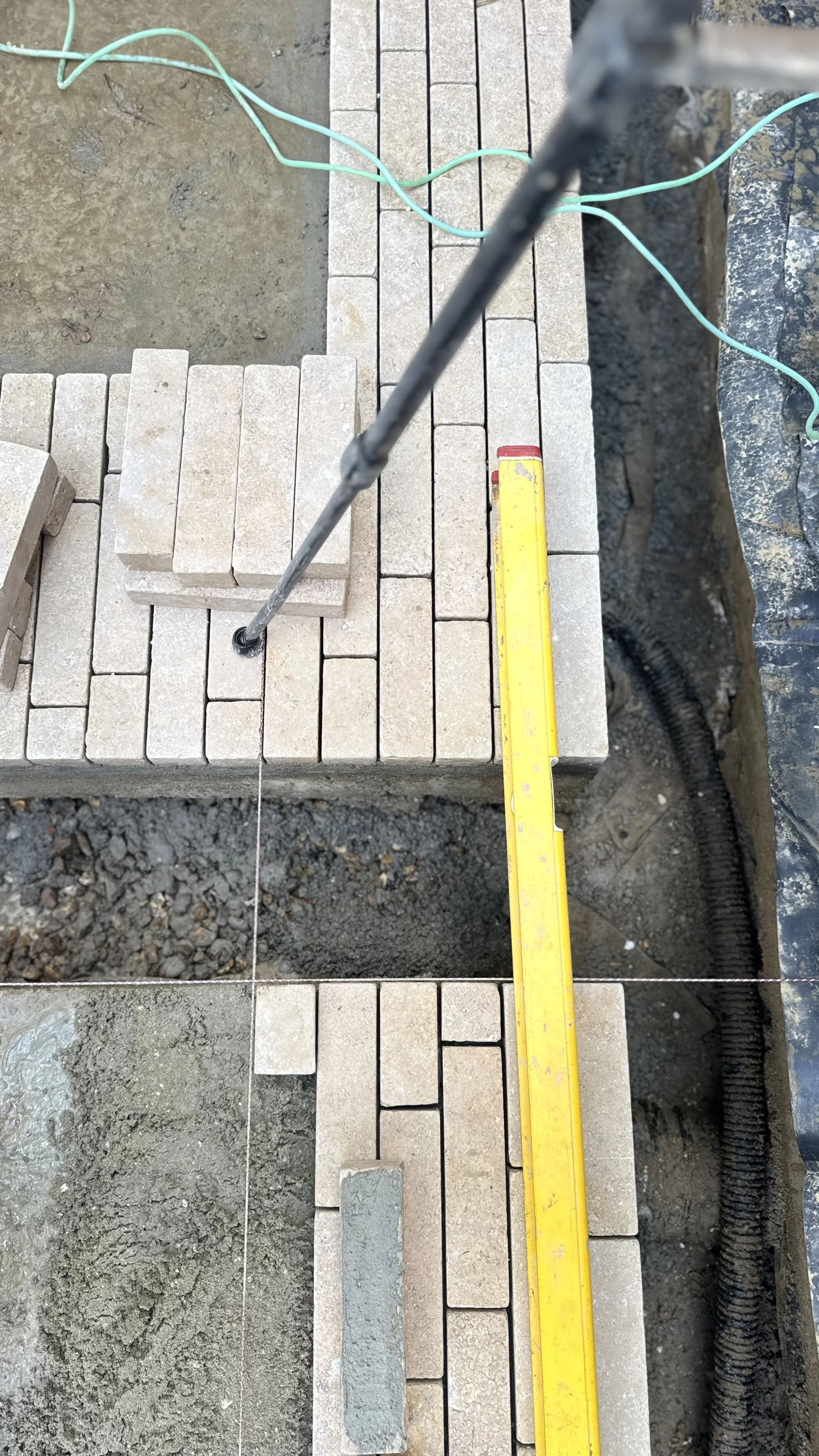 Construction site with brick pavers, a level, and a string line for bricklaying