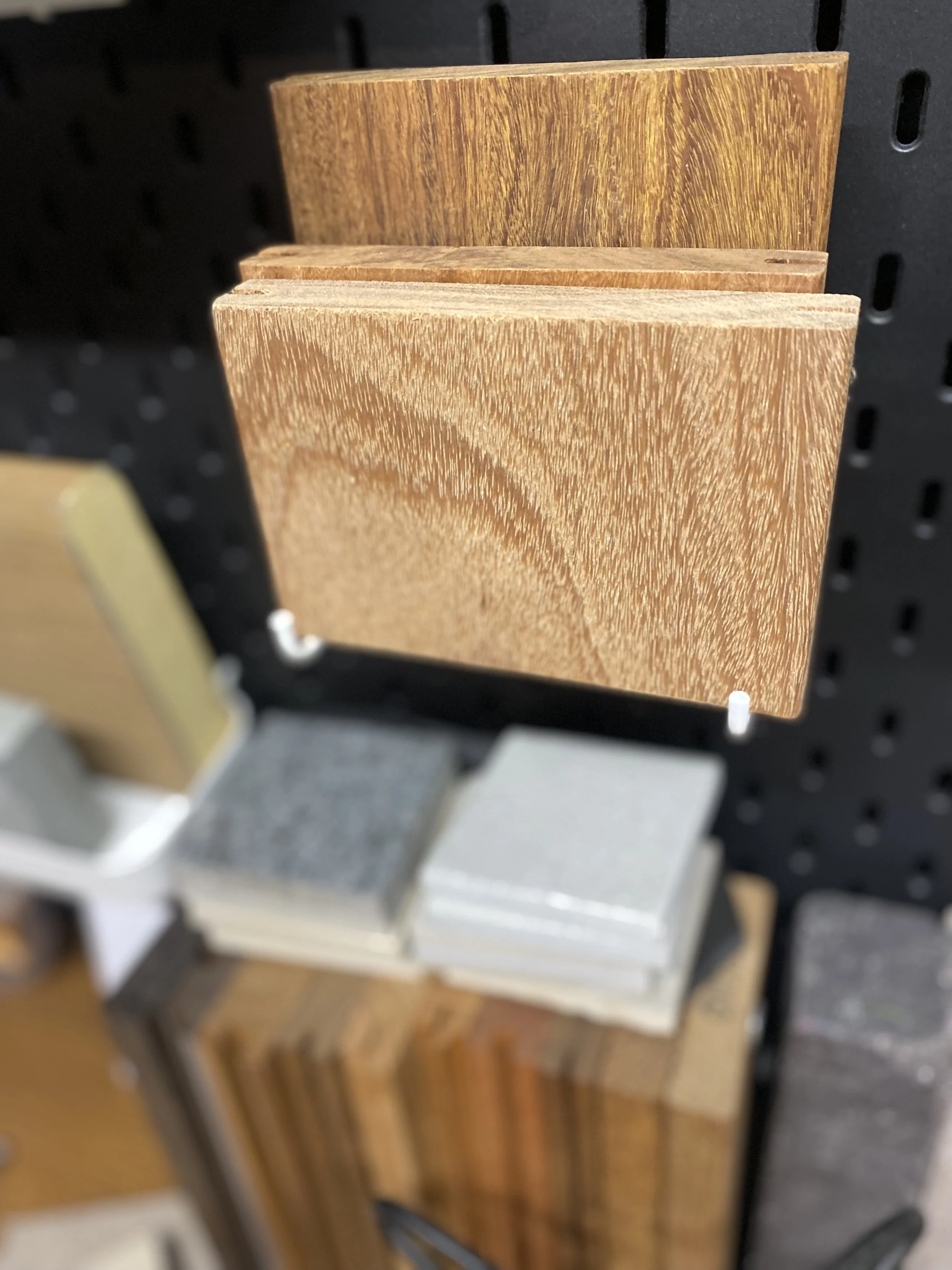 Sample wood veneer swatches in different shades displayed on a pegboard.