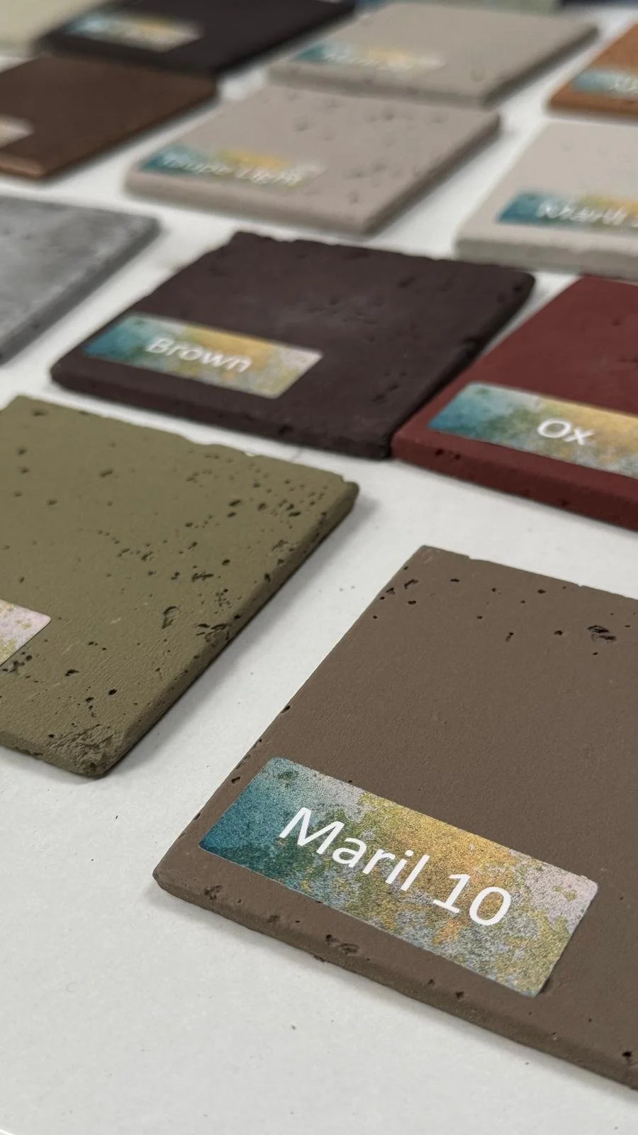 Color swatches of various shades, including brown, red, and beige, with labels such as 'Maril 10', arranged on a white surface.